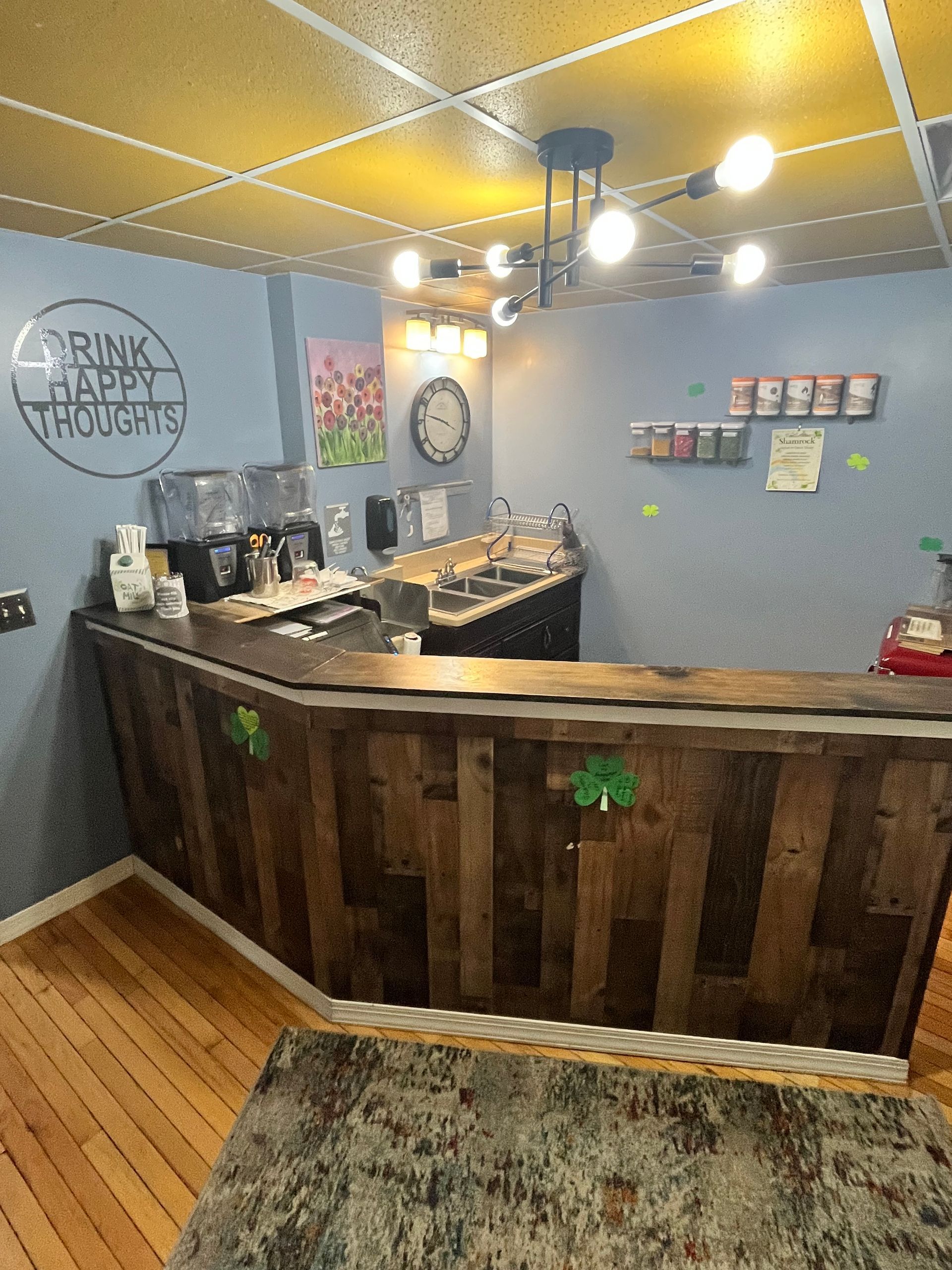 A rustic wooden home bar with blue walls, a dark ceiling, a pendant light, a sink area, and wall decor.