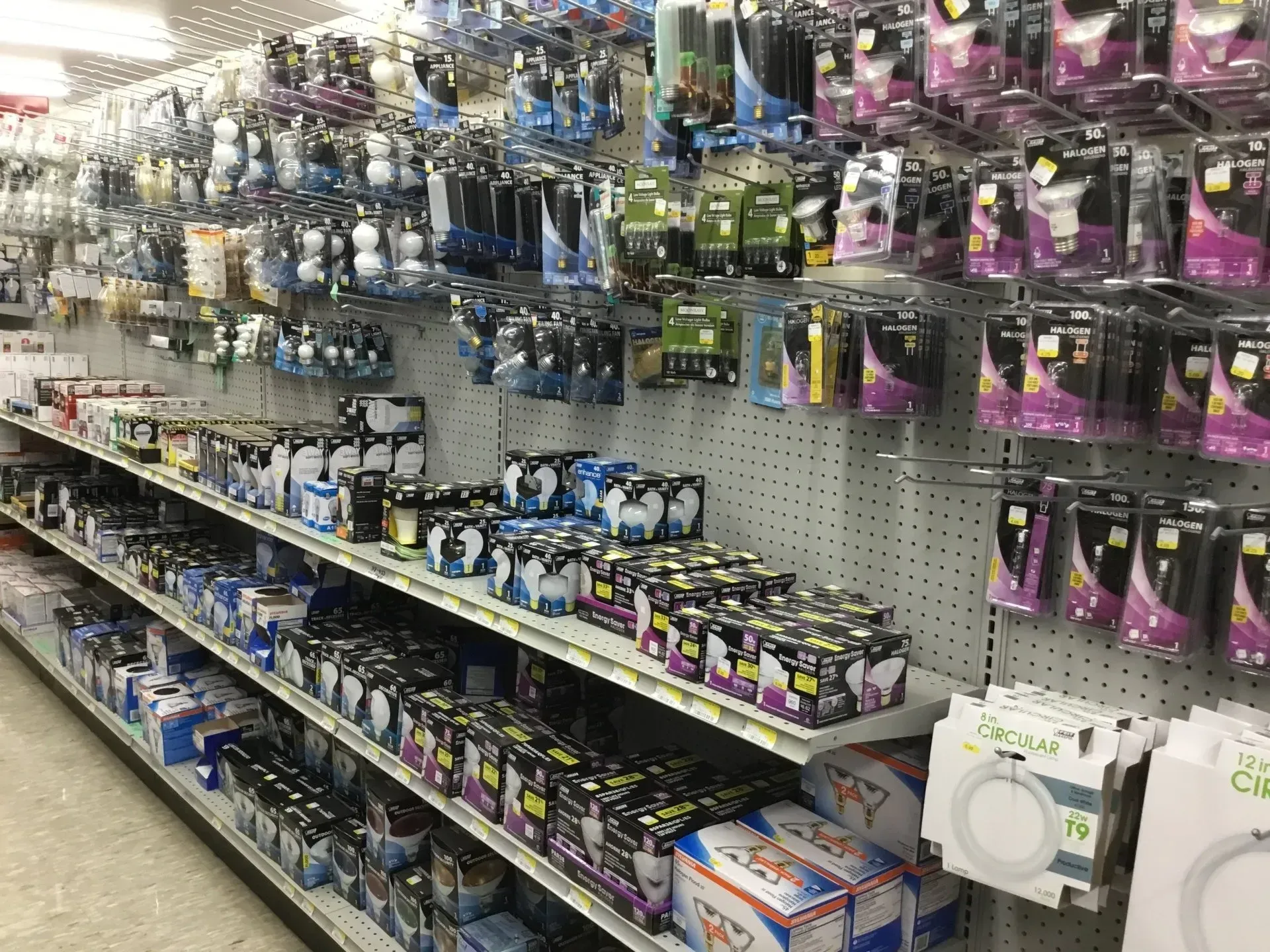 Store aisle with rows of hanging packaged accessories on pegboard shelves.