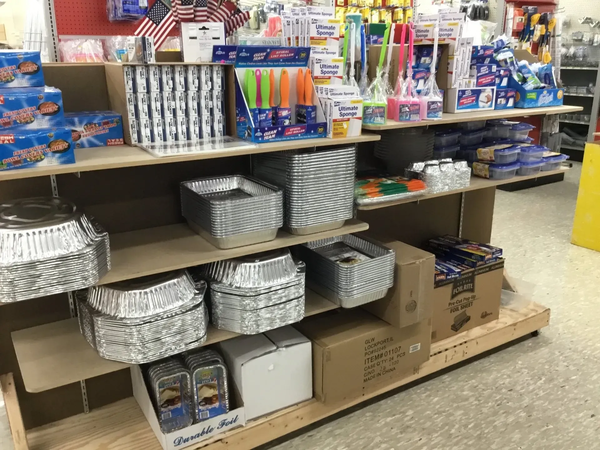 Store shelf stocked with foil pans, plastic party supplies, and other kitchen goods