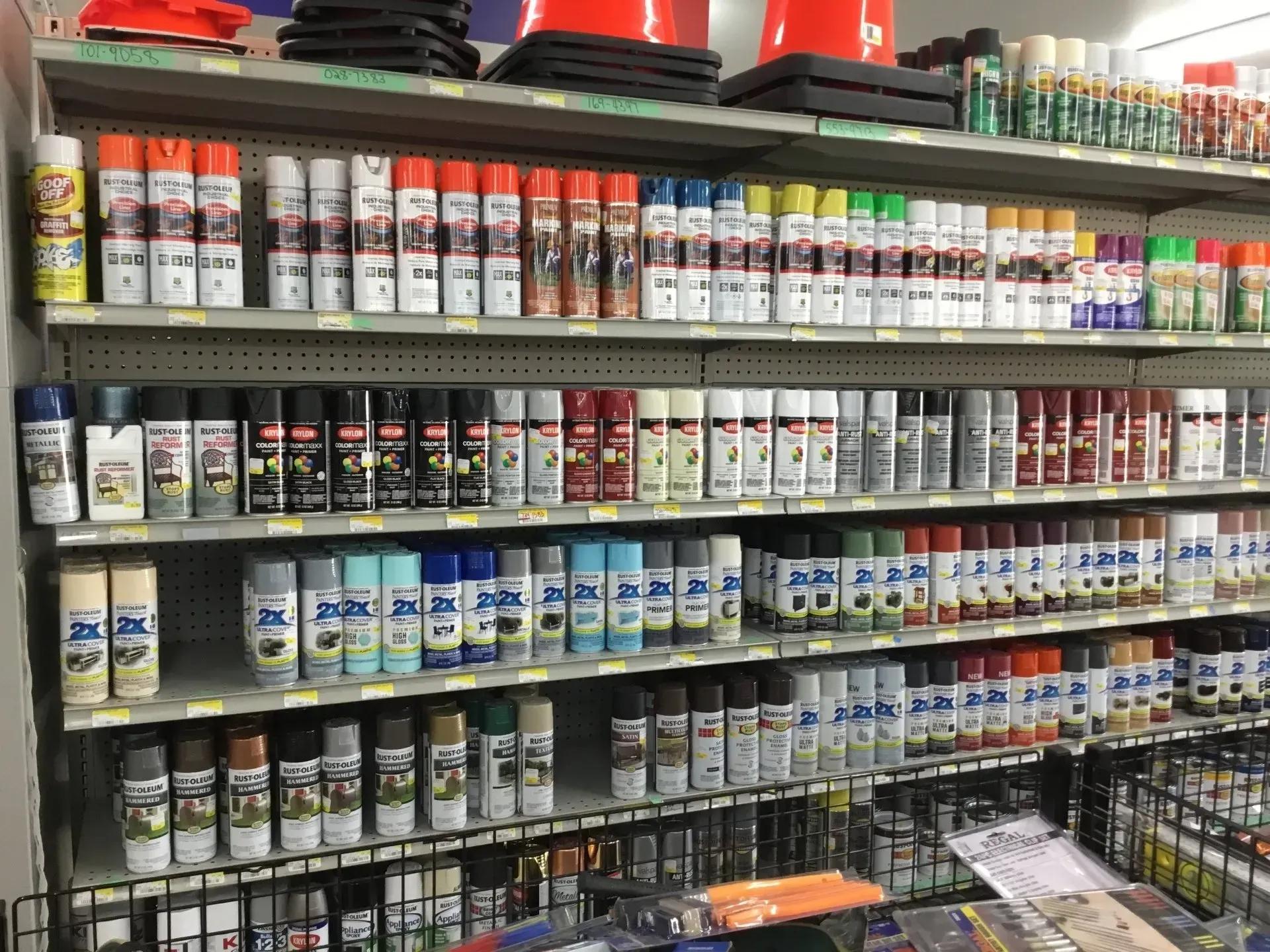 A hardware store aisle with shelves stocked with rows of spray paint cans and other paint products.