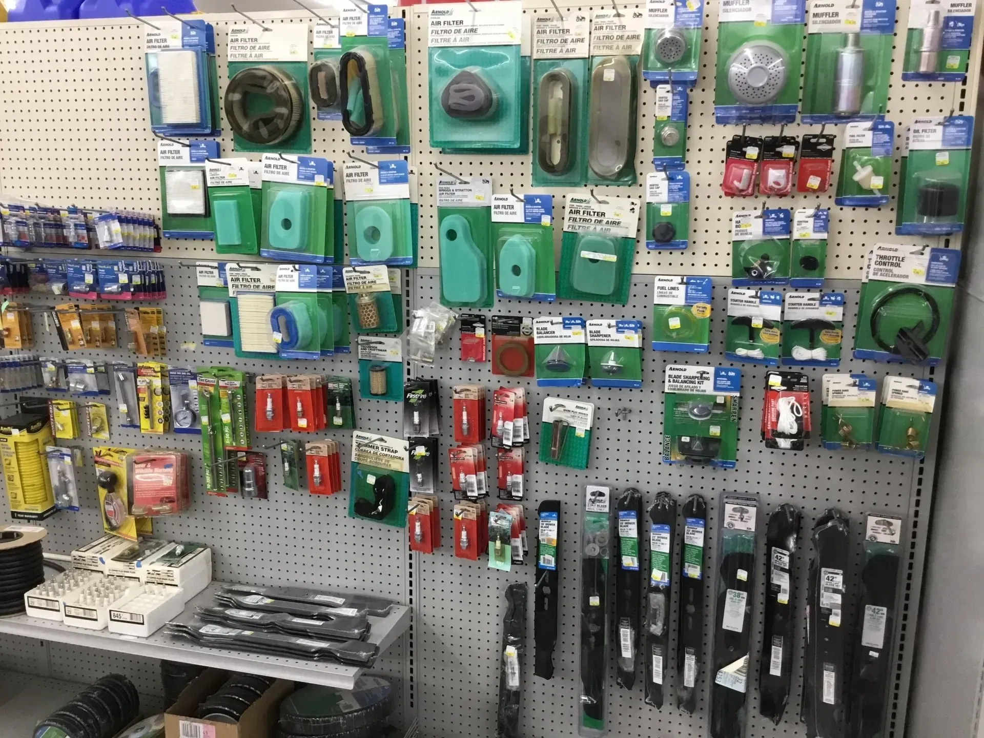 Wall of packaged hardware accessories on pegboards in a store aisle, with tools and parts in green, red, and black.