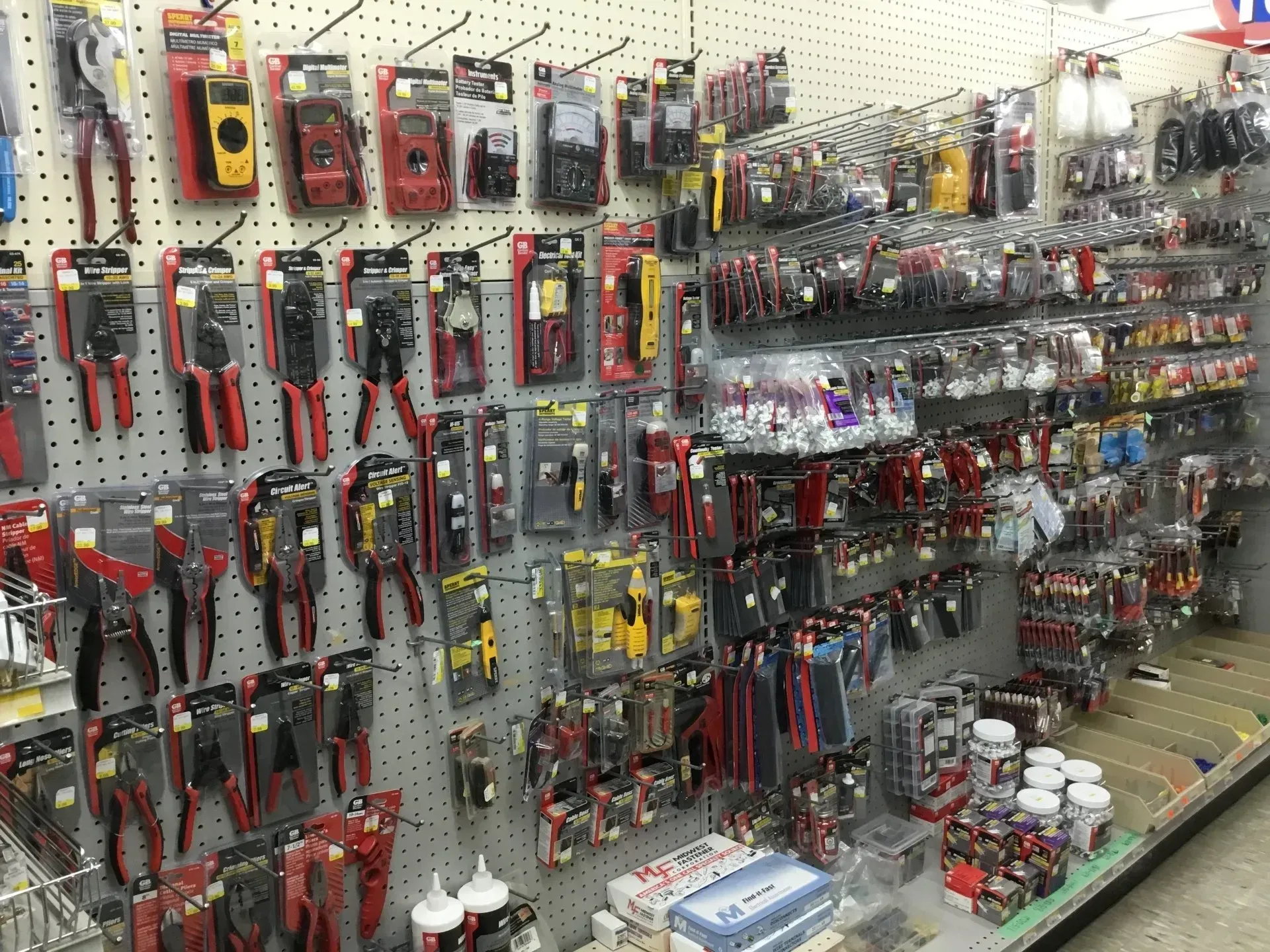 Hardware store aisle with tools and accessories on pegboard displays and shelves