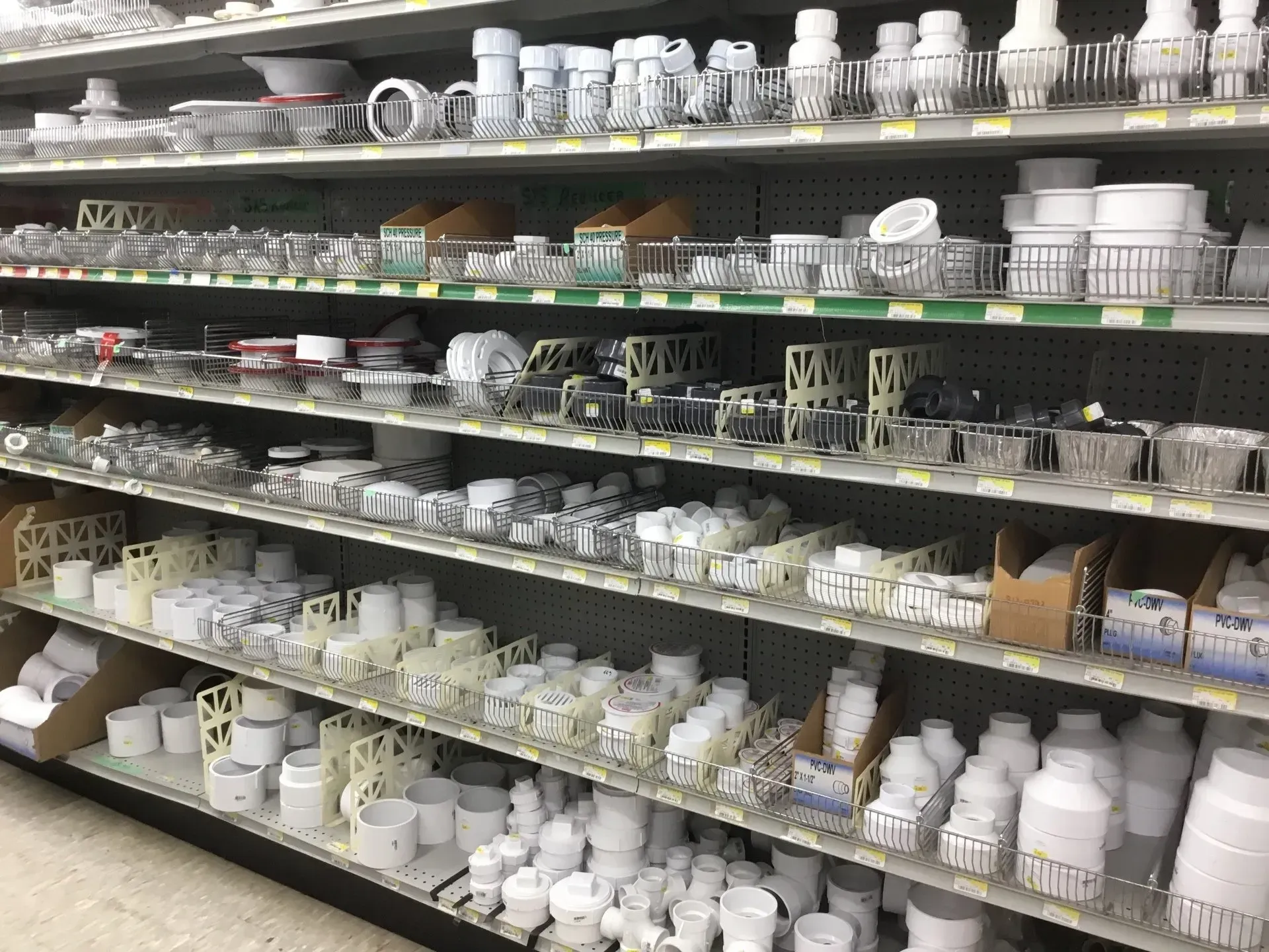 Store aisle with shelves of white dishes, cups, and kitchenware displayed in rows