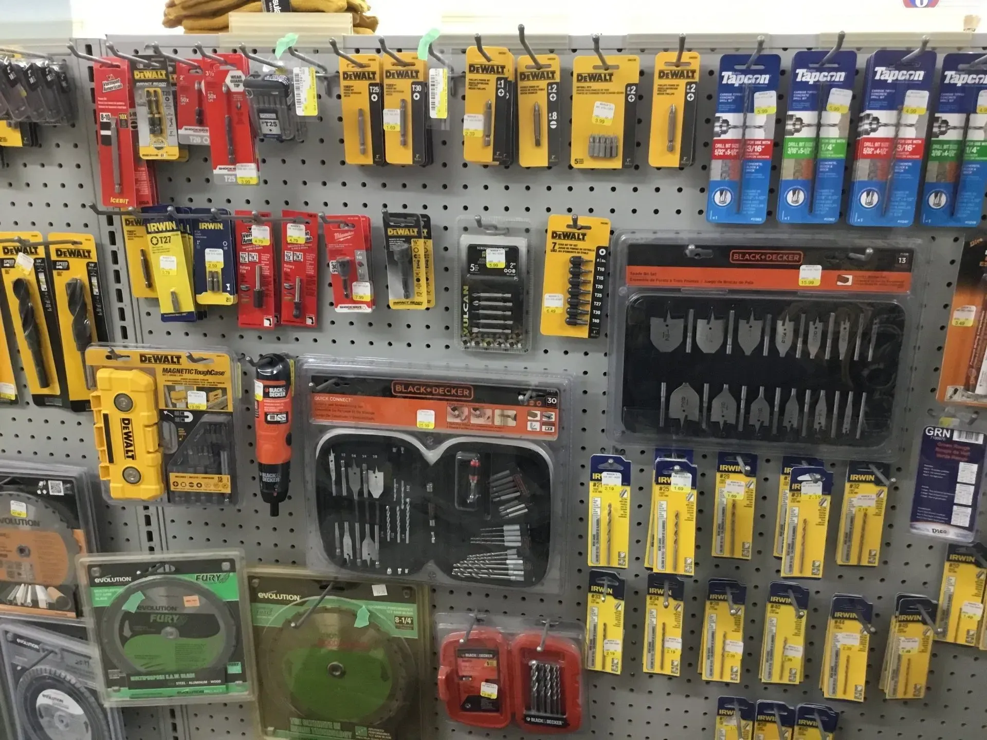 Hardware store display of hanging tool sets and accessories in yellow, red, black, and blue packaging.