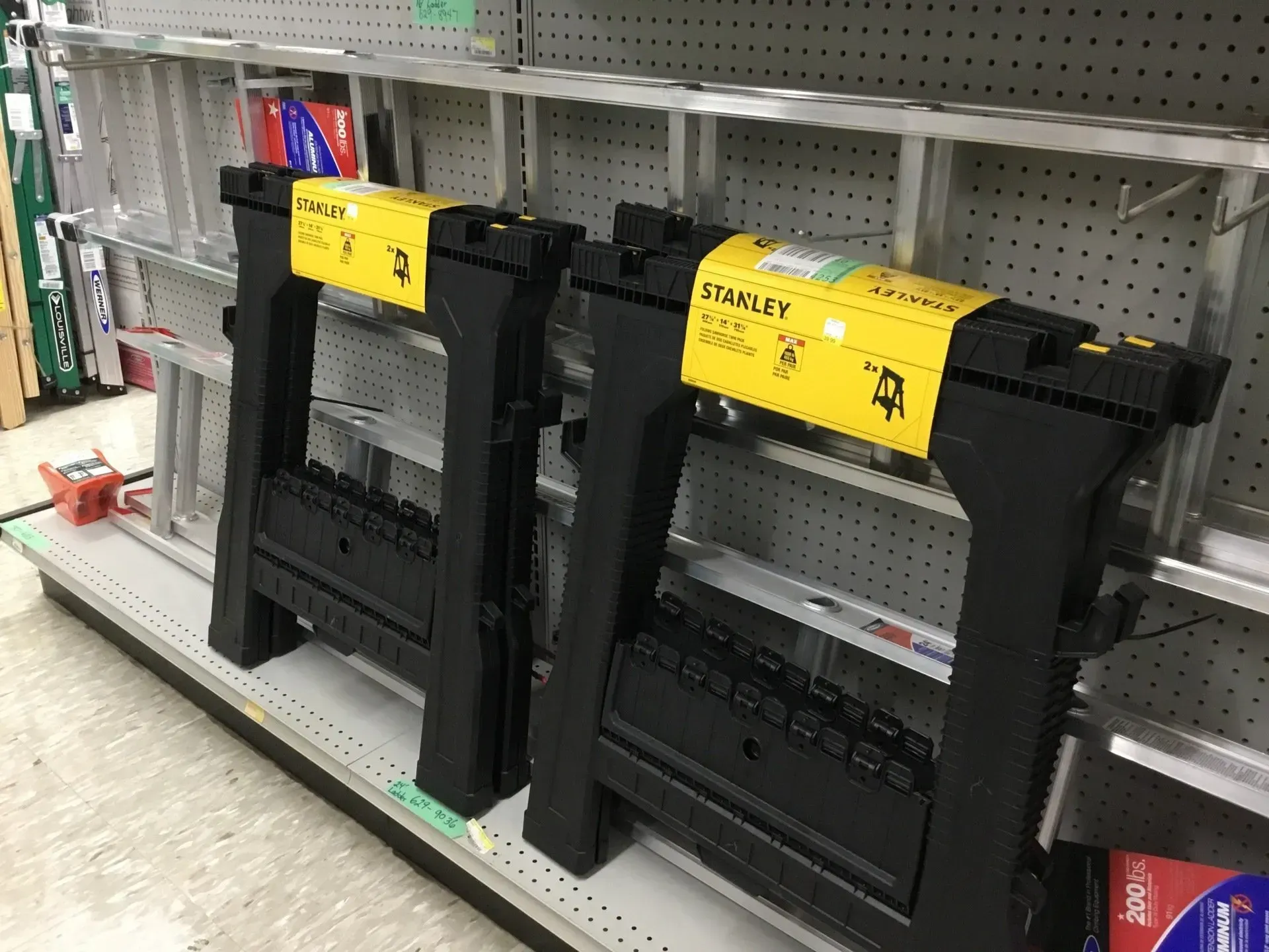 Black and yellow display fixtures on a store shelf, with pegboard backing and books in the background