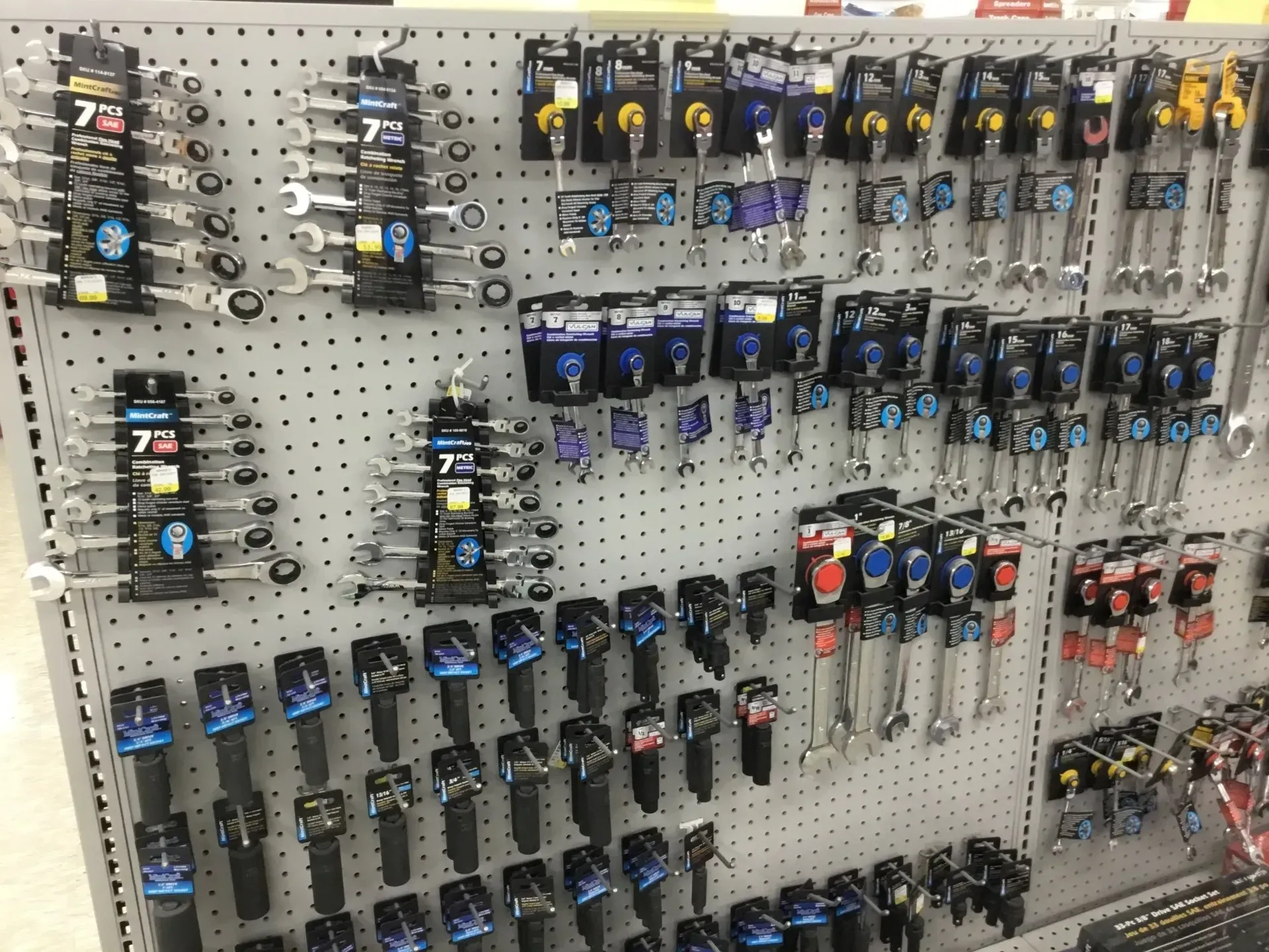 Pegboard display of packaged tools and accessories hanging in a hardware store aisle