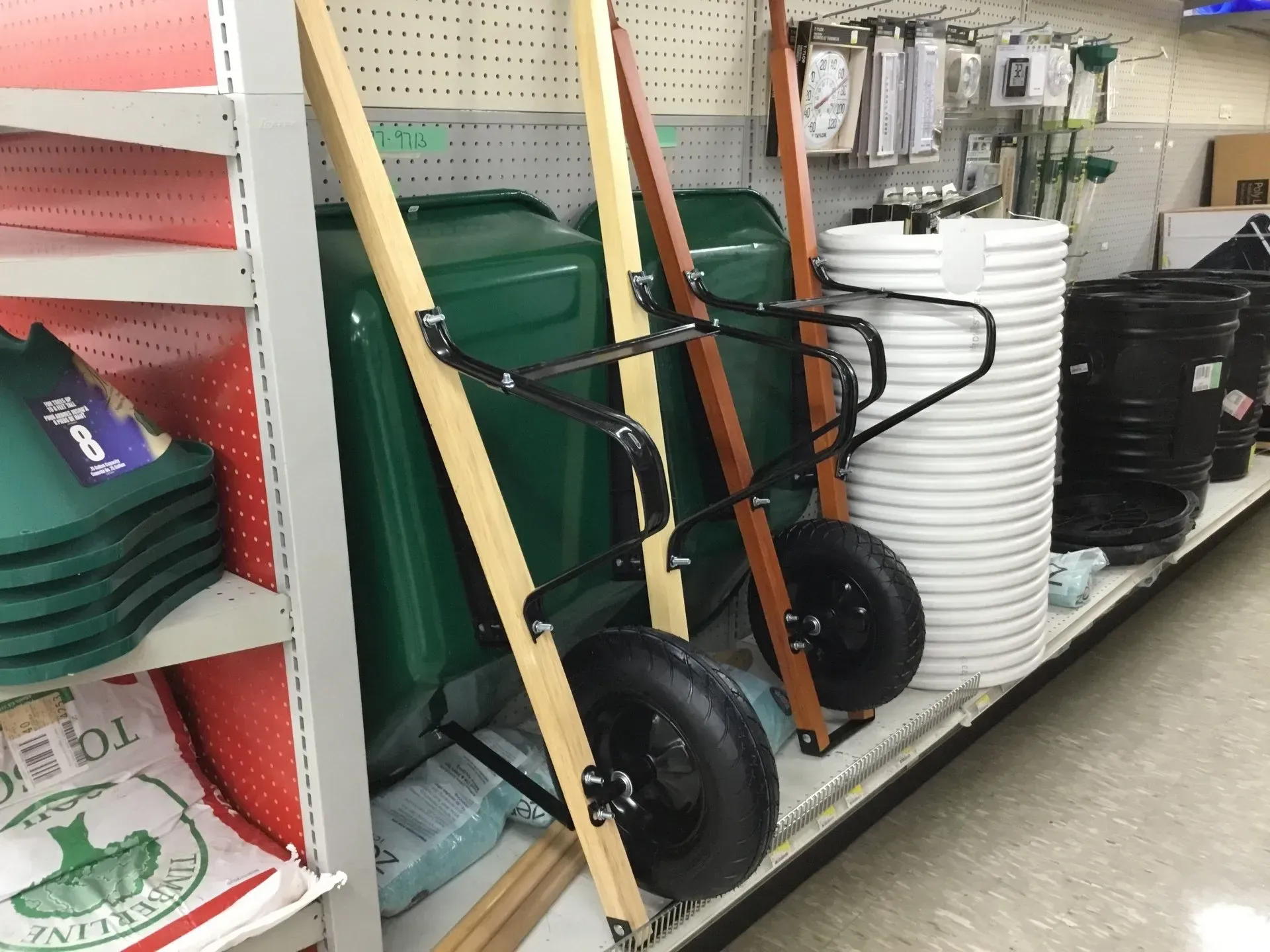 Hand trucks with wood handles and black wheels displayed on a store aisle shelf