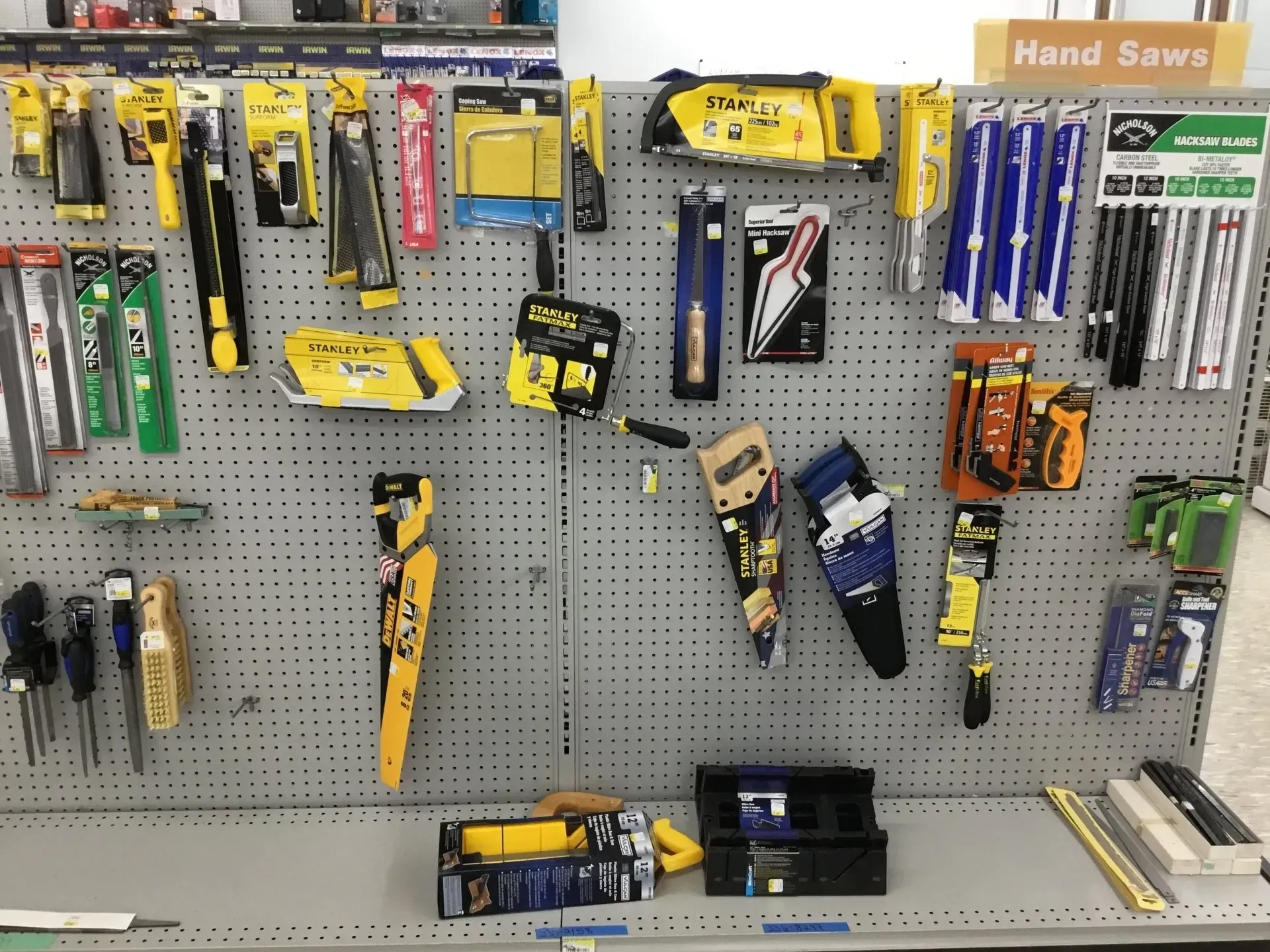 Hardware store aisle with assorted hand saws and cutting tools displayed on a pegboard.