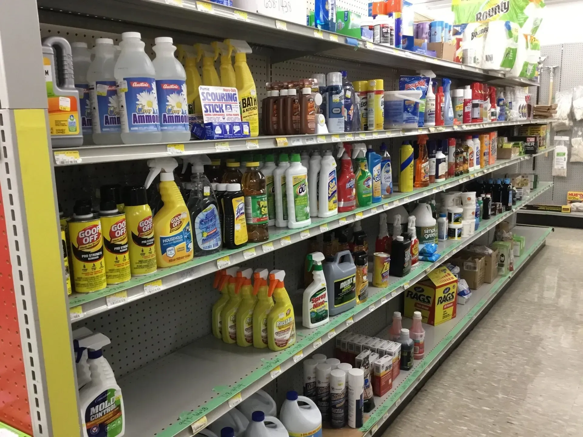 A store aisle stocked with cleaning supplies, detergents, and bottles on metal shelves.