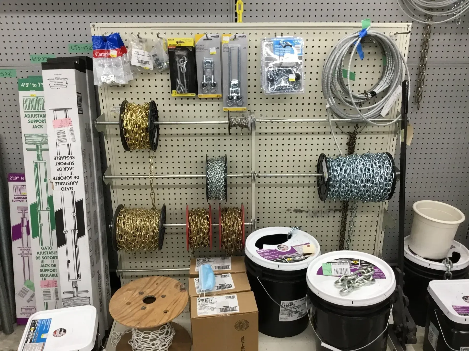 Pegboard display of assorted cords, wire spools, hooks, and a white mug in a store aisle