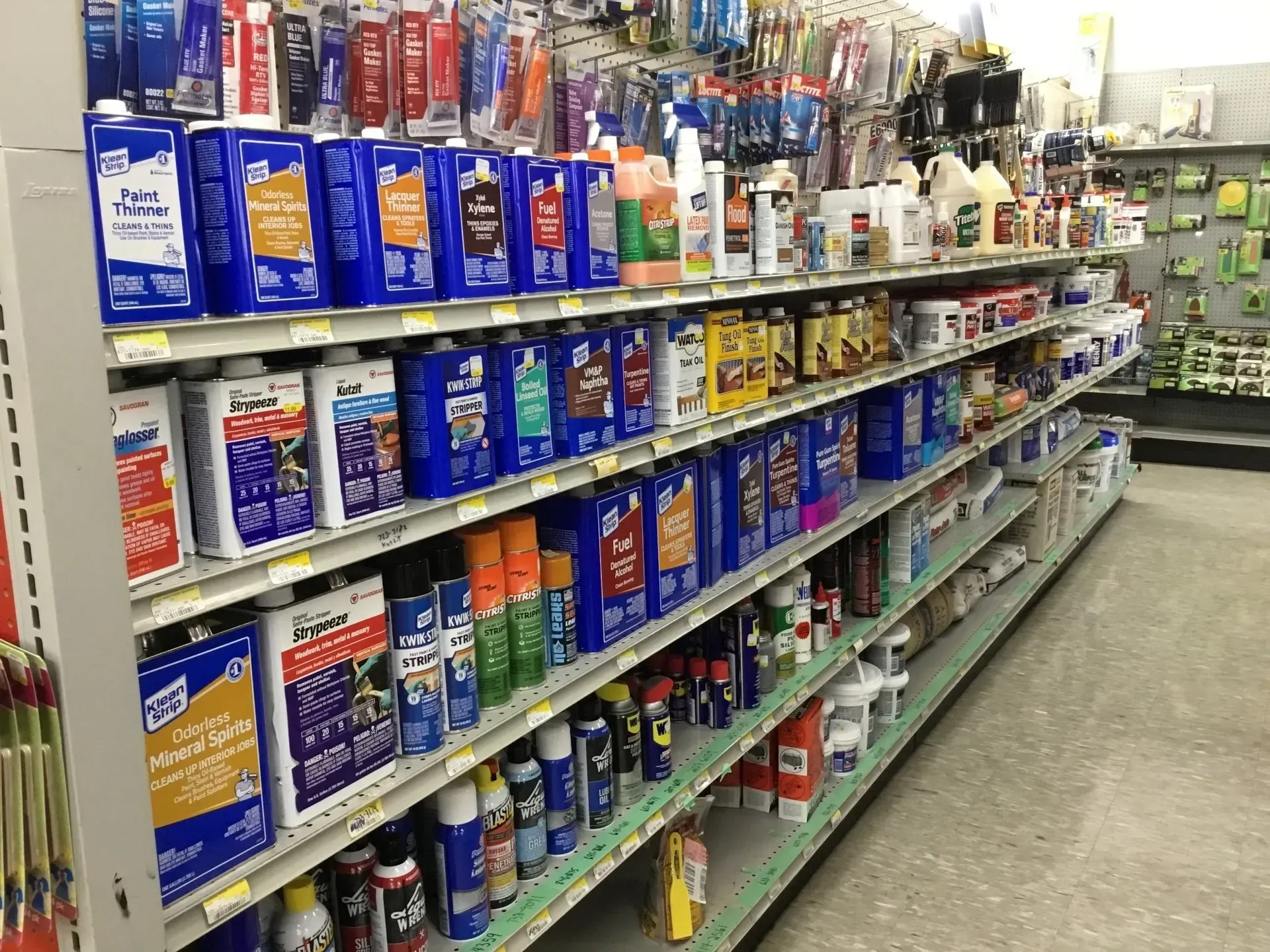 A store aisle with shelves stocked with car care and cleaning products in colorful bottles and cans.