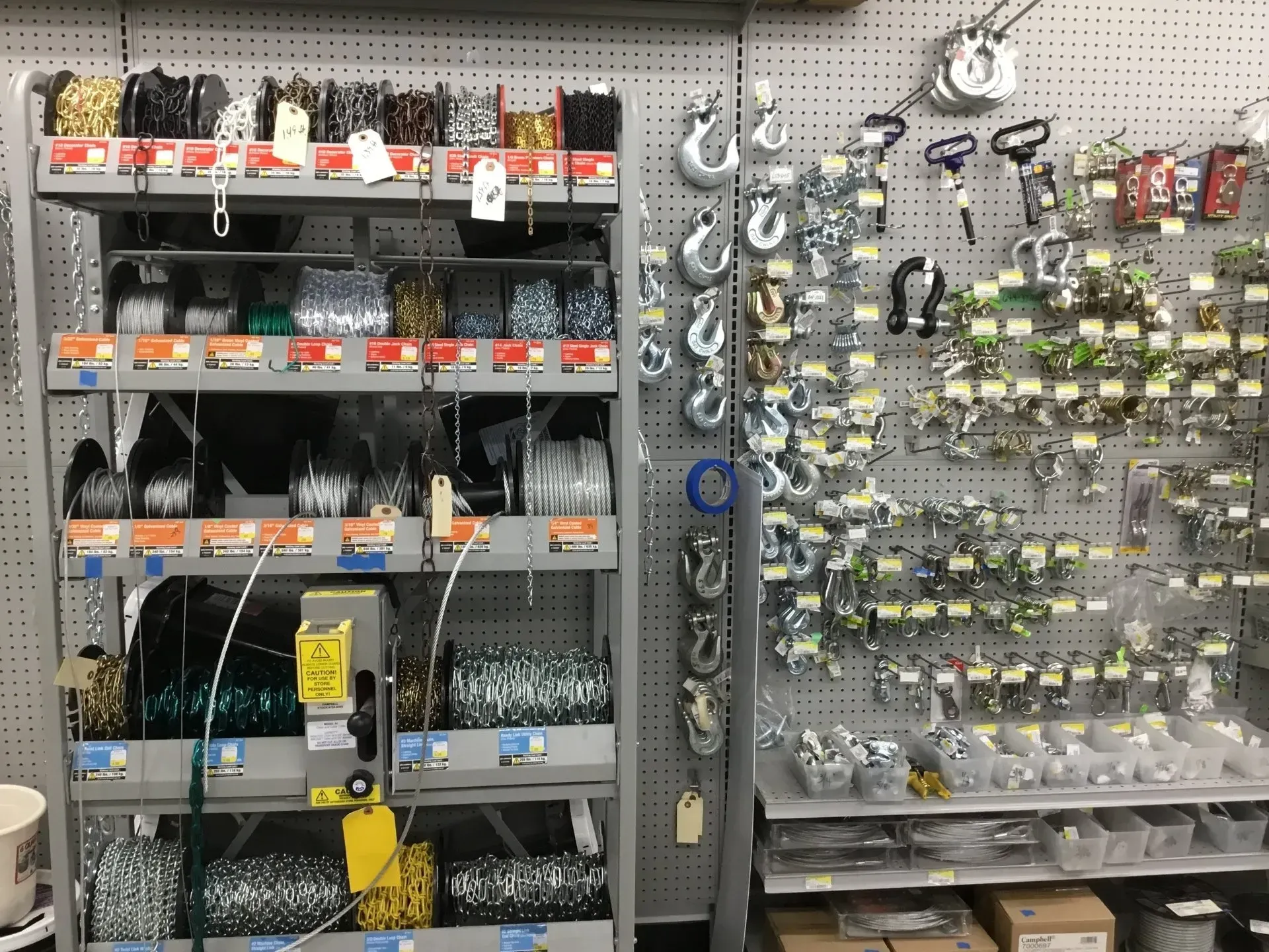 Hardware store aisle with shelves of tools, fasteners, and hanging keychains.