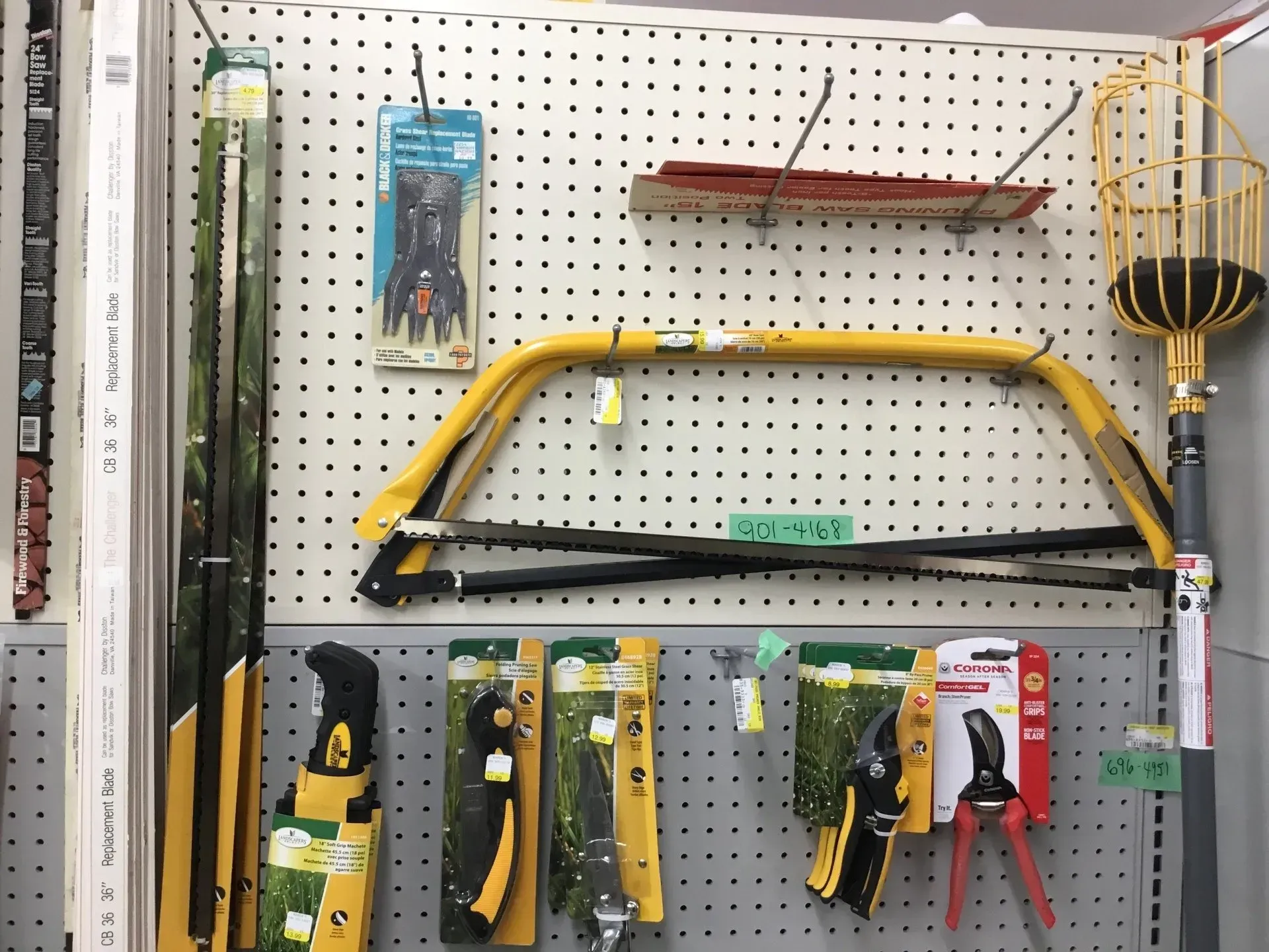 Pegboard display of assorted hand tools, including saws and cutters, hanging in a store aisle