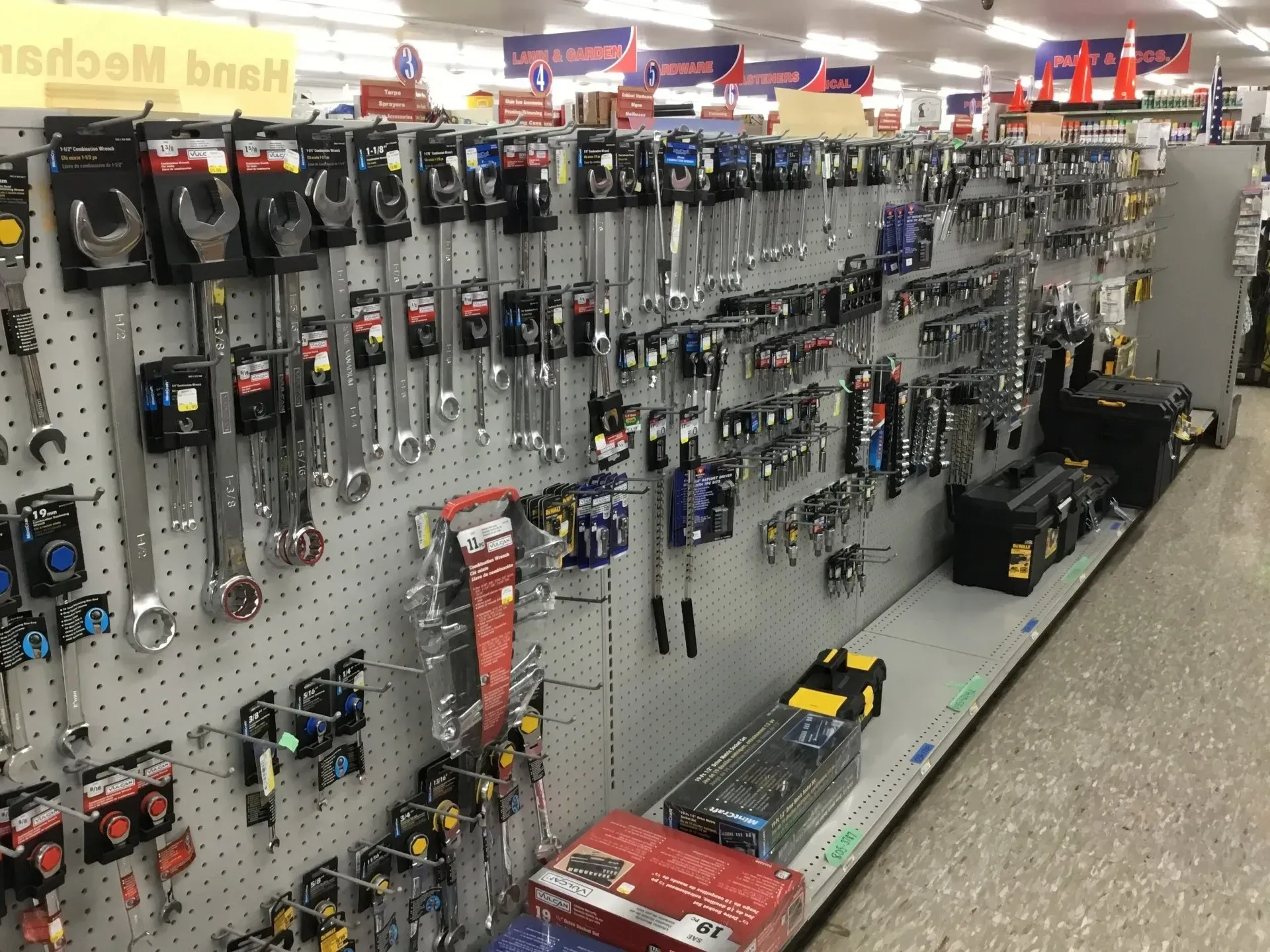 Hardware store aisle with tools and accessories displayed on pegboard shelves, including clamps and drills.