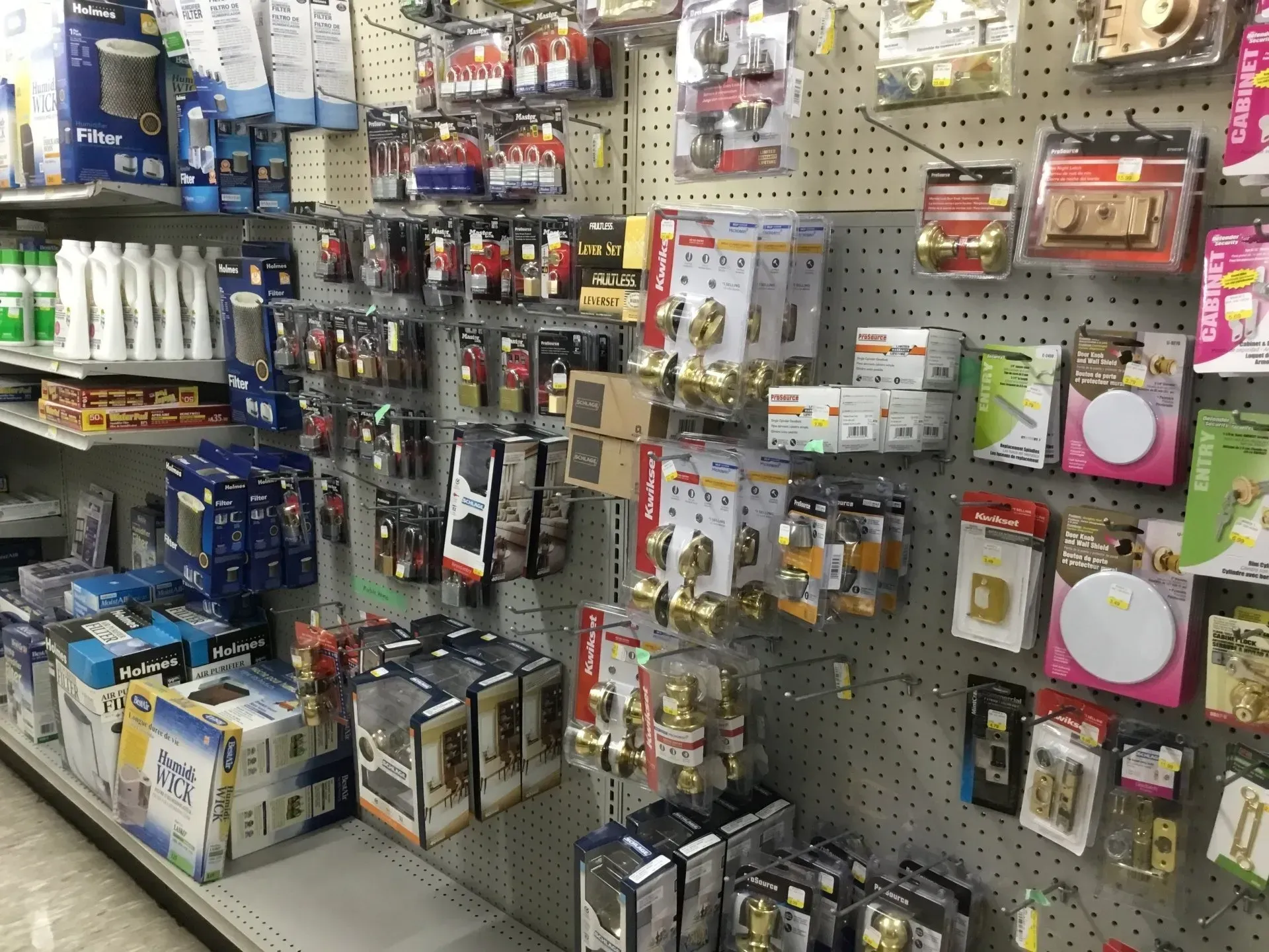 Hardware store aisle with hanging power tools, tape measures, cords, and boxed supplies on pegboard shelves.