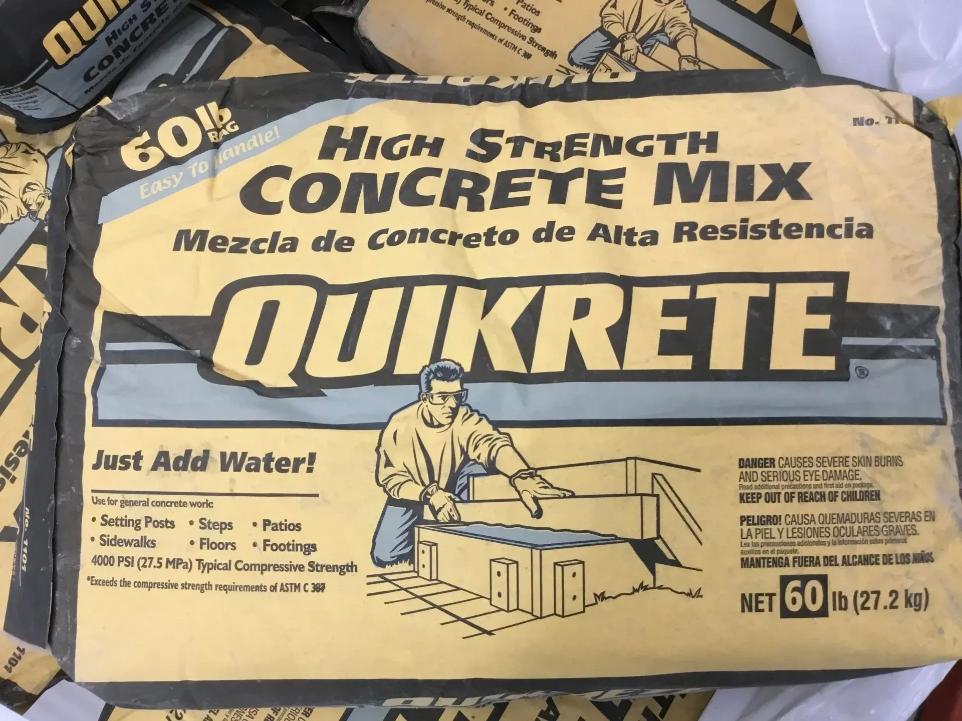 Bag of QUIKRETE high strength concrete mix, yellow and blue packaging with worker illustration.