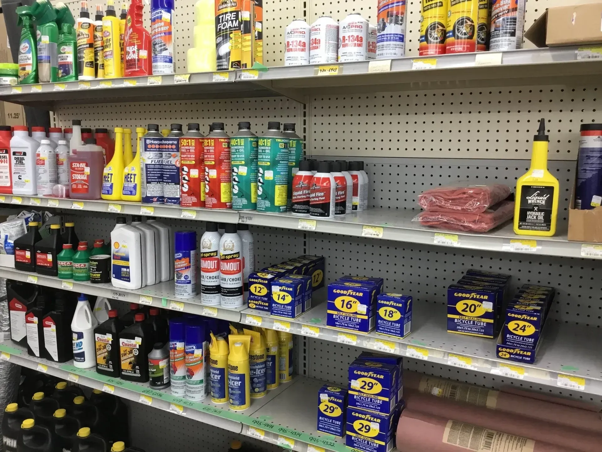 Store shelf stocked with car care products, spray cans, oils, and cleaning supplies in a hardware aisle