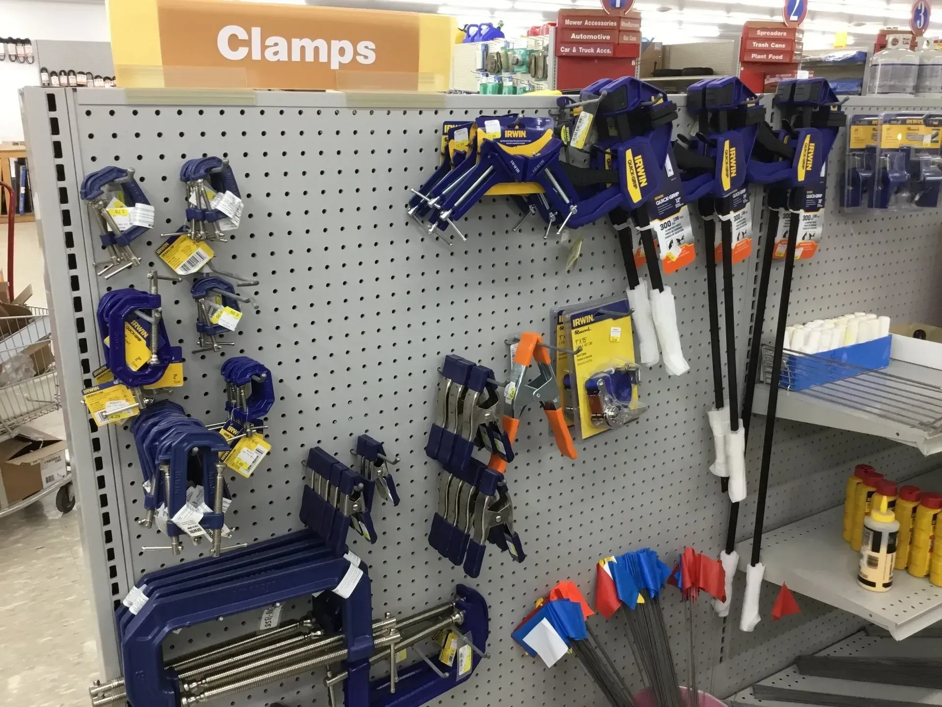Hardware store clamp display with blue-and-yellow clamps hanging on a pegboard shelf