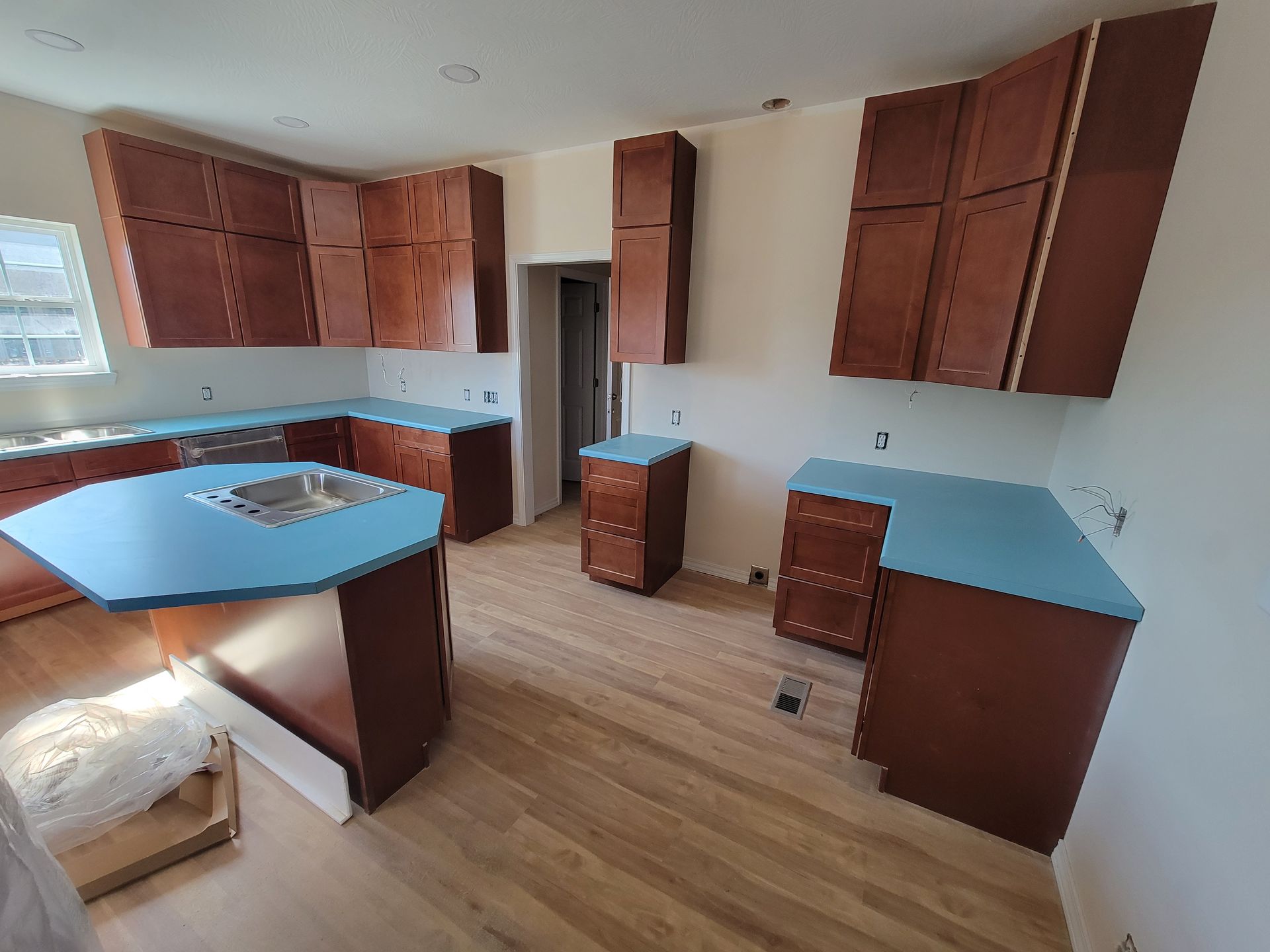 Kitchen with brown cabinets, light blue countertops, and light wood floors.