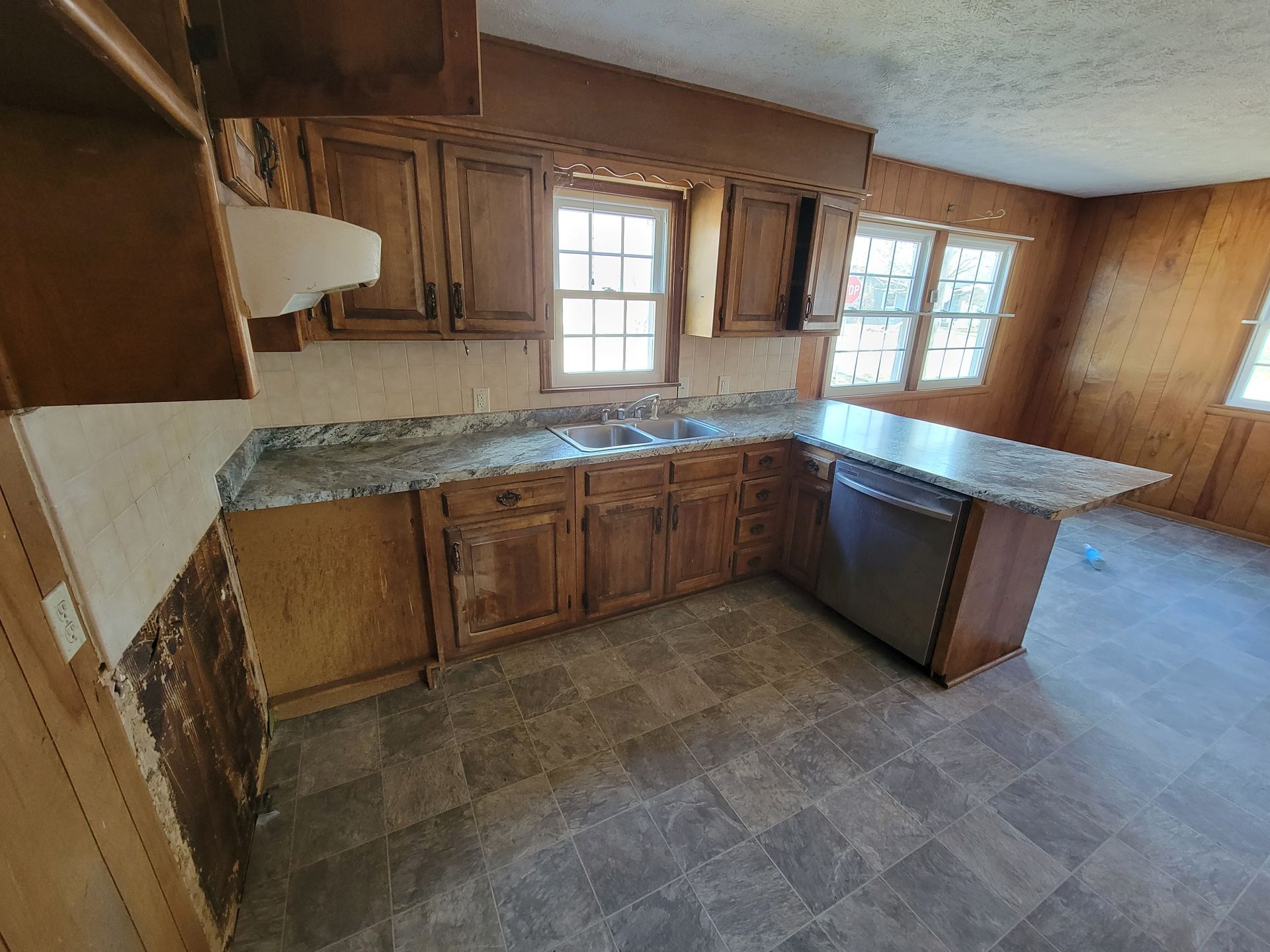 Kitchen with wooden cabinets, granite countertops, and a stainless steel dishwasher.