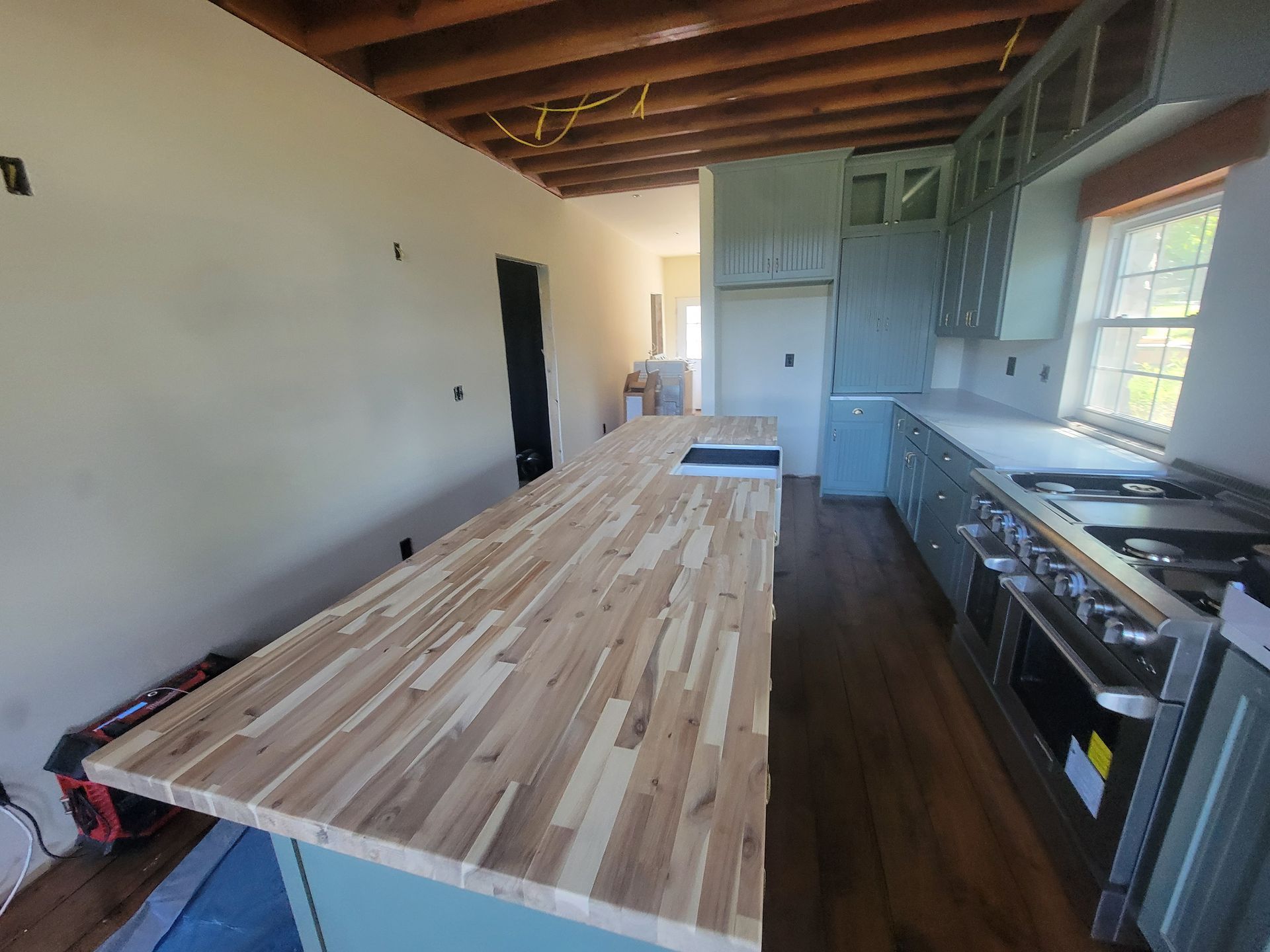 Kitchen renovation: light wood island countertop, pale blue cabinets, stainless steel appliances, and cream walls.