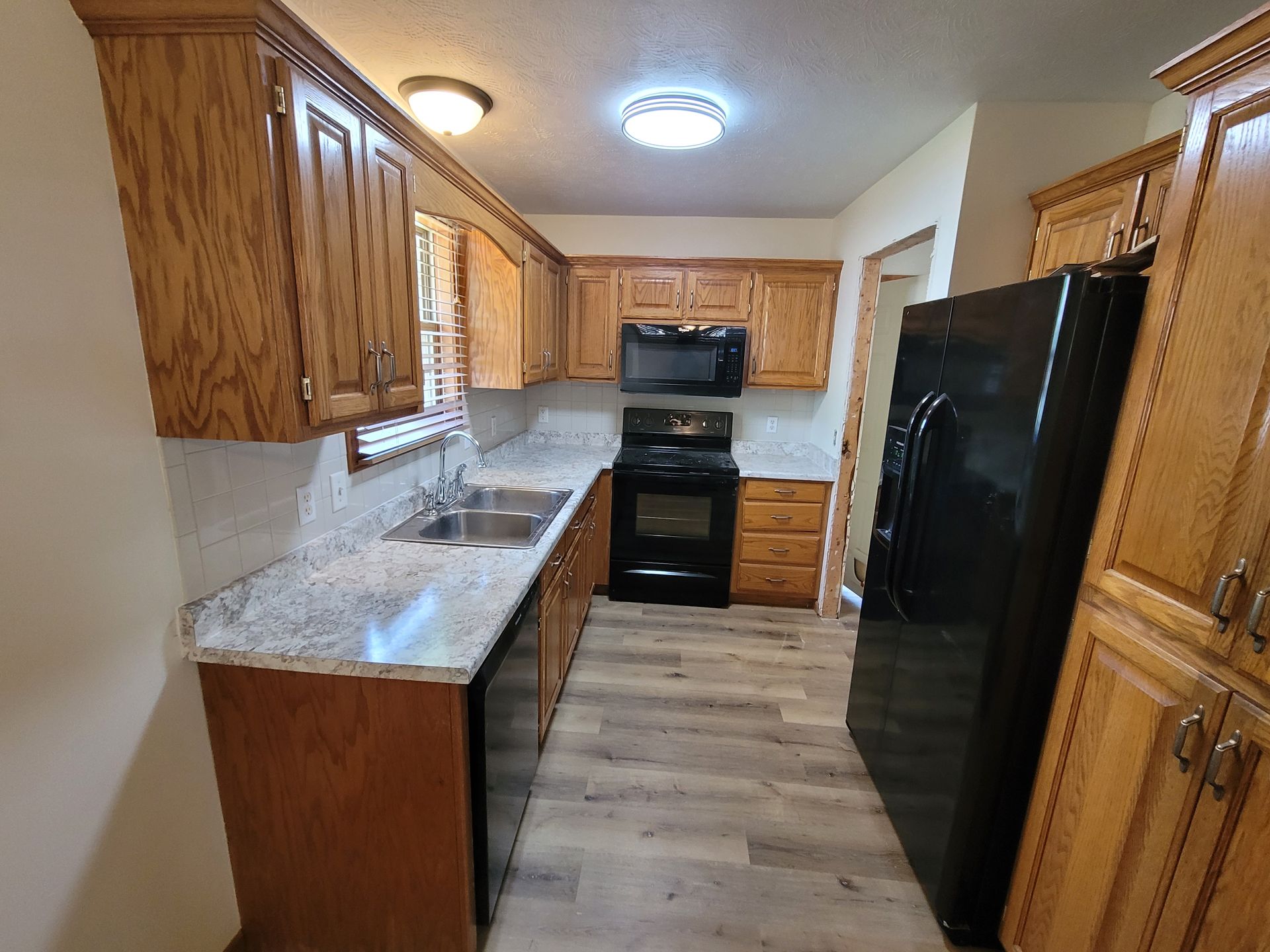 Small kitchen with wooden cabinets, granite countertops, and black appliances.