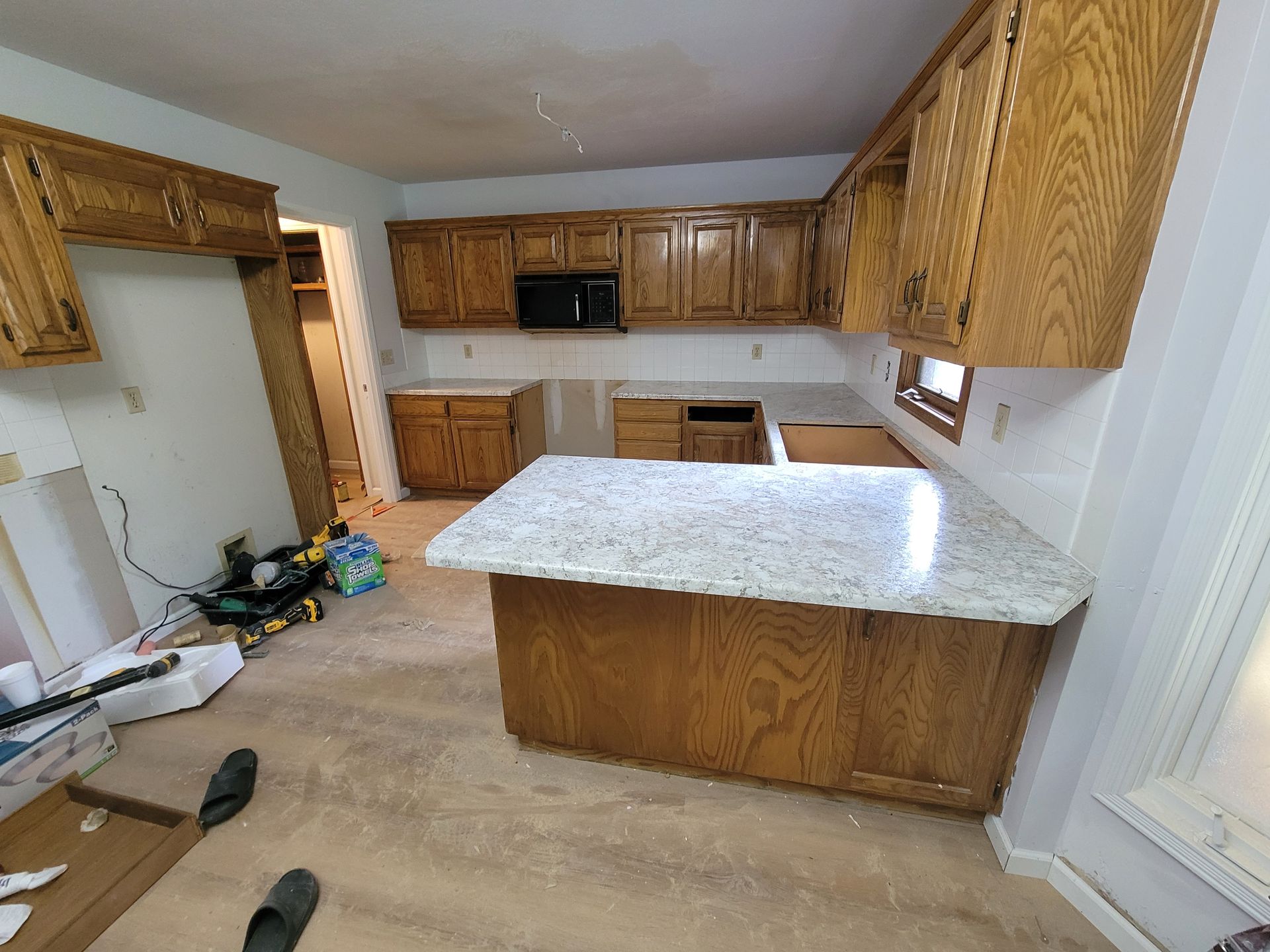 Kitchen renovation in progress, featuring oak cabinets, granite countertops, and visible construction materials.