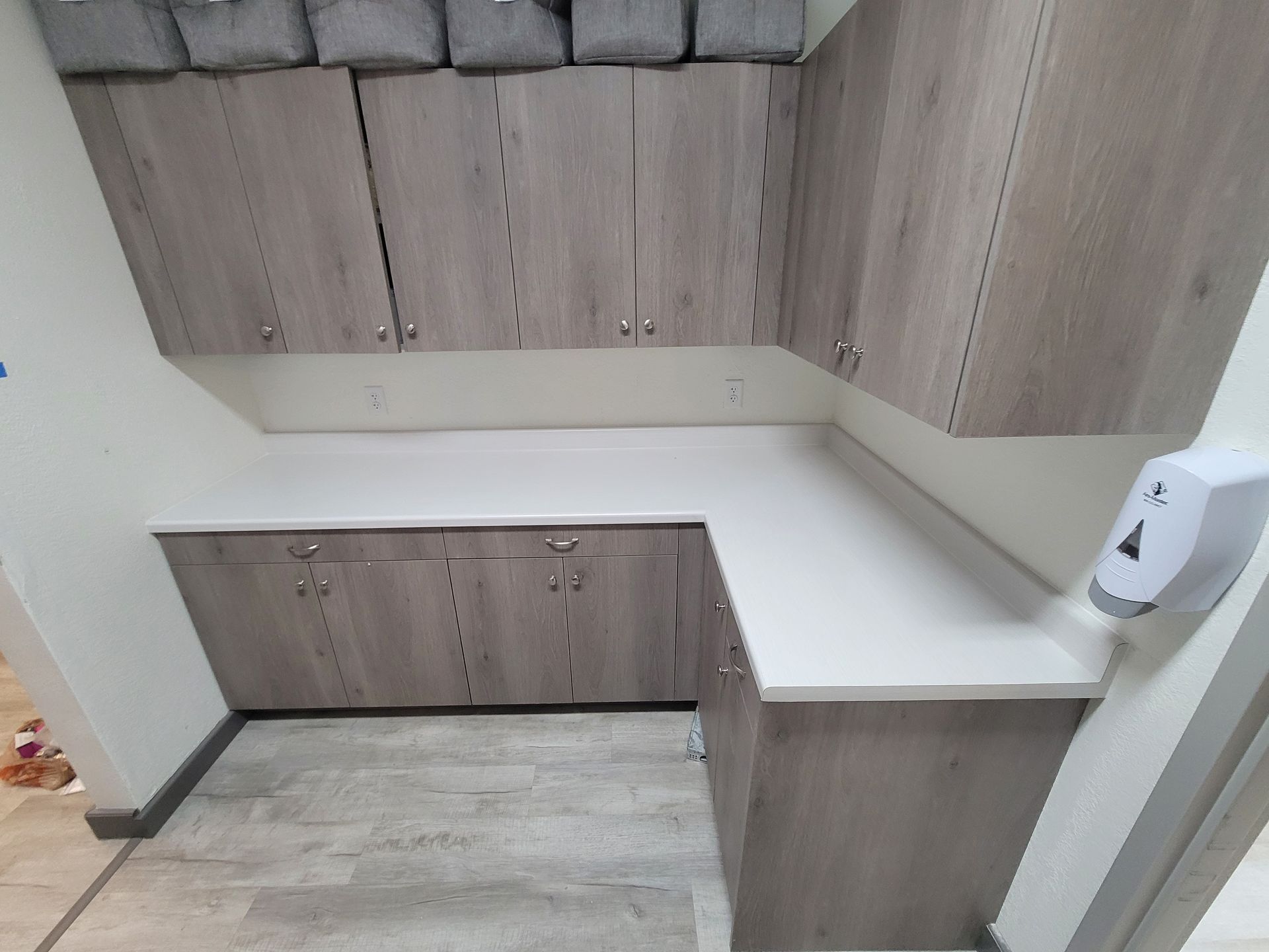 L-shaped cabinetry with wood-look doors and white countertop in a room.