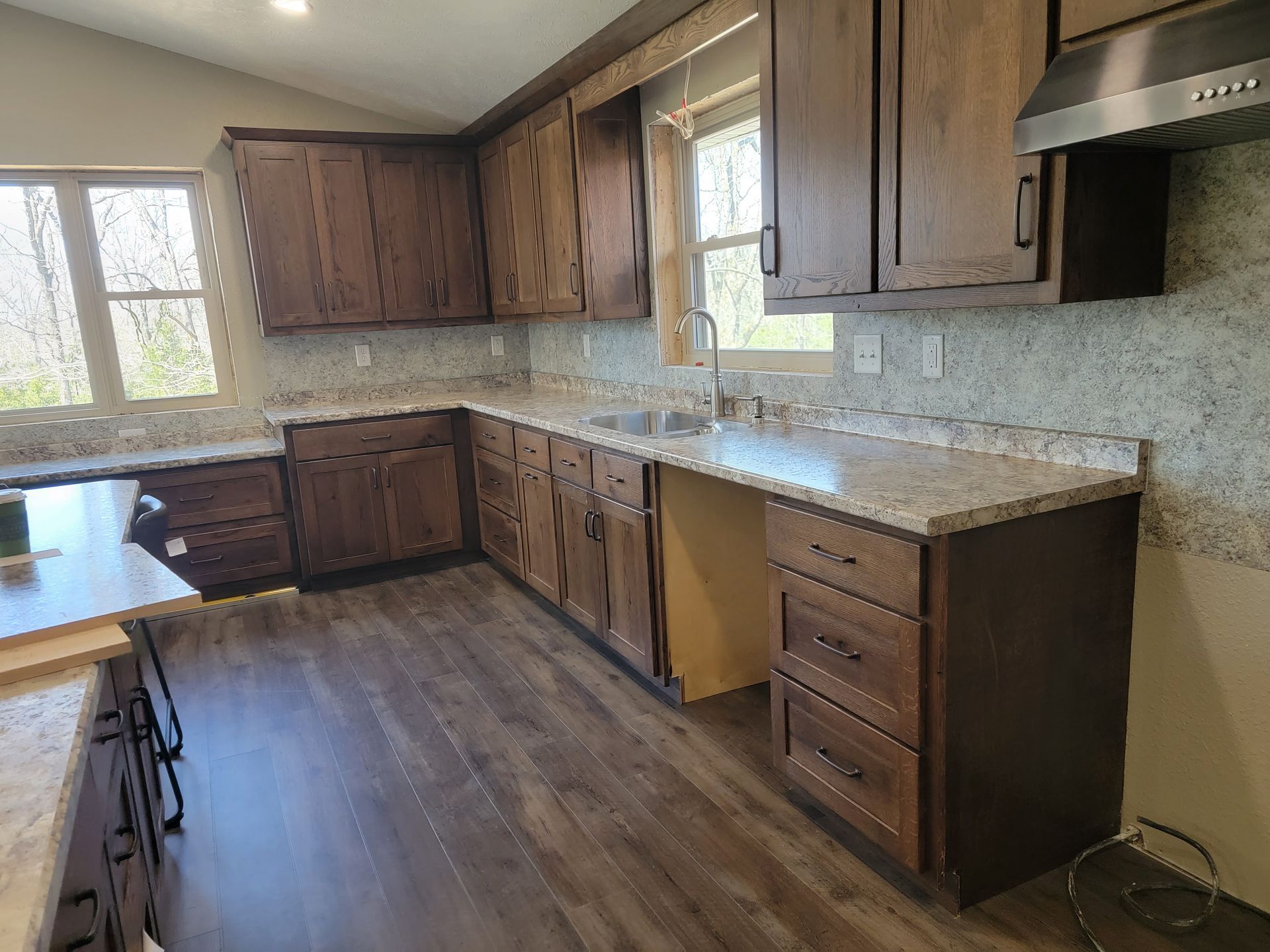 Kitchen with dark wood cabinets, light countertops, and a window.