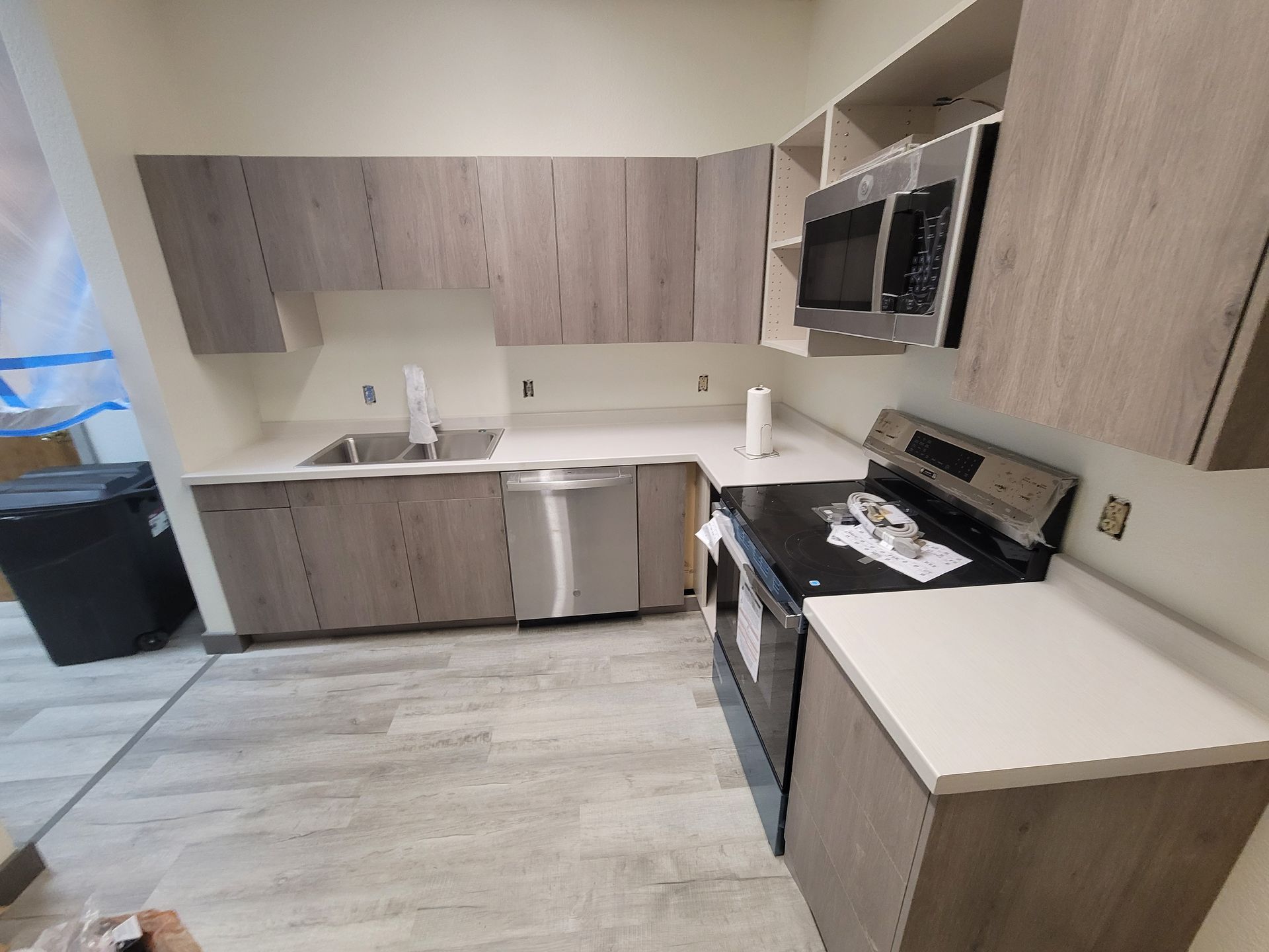 Kitchen with light gray cabinets, white countertops, stainless steel appliances, and wood-look flooring.