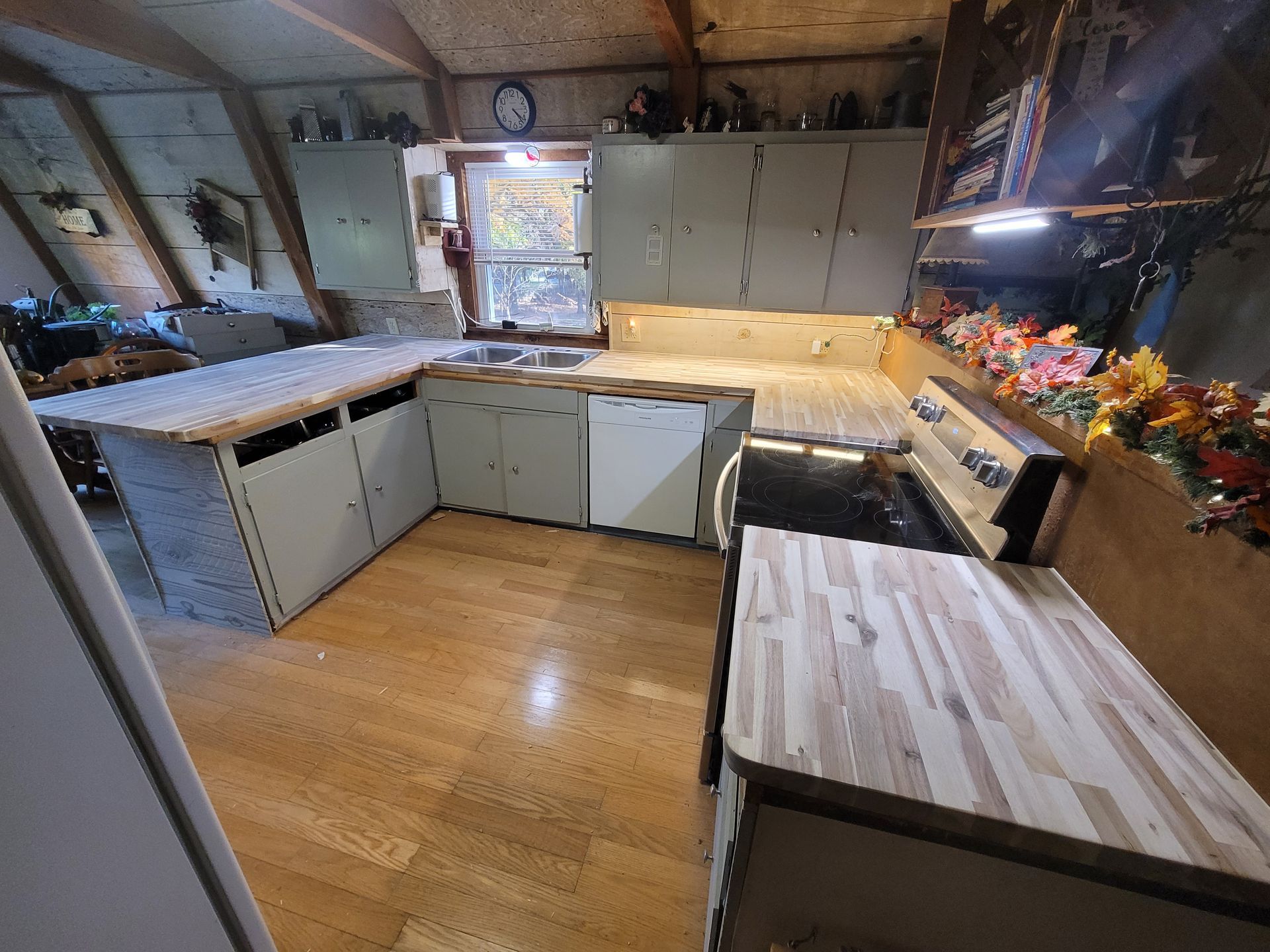 U-shaped kitchen with light wood countertops, gray cabinets, and a black stove. Doorway visible in the center.