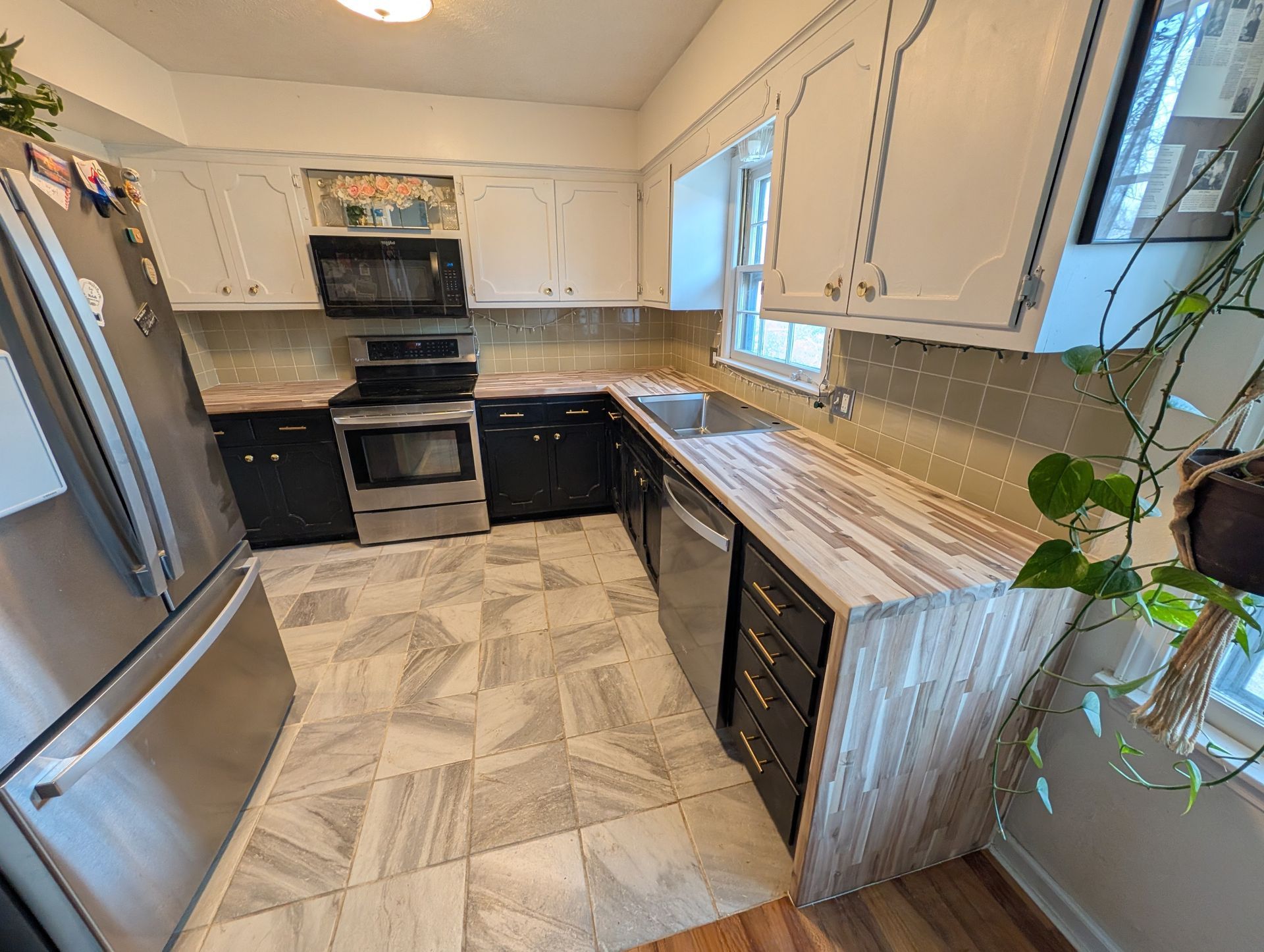 Kitchen with white and black cabinets, stainless steel appliances, and tile backsplash and floor.