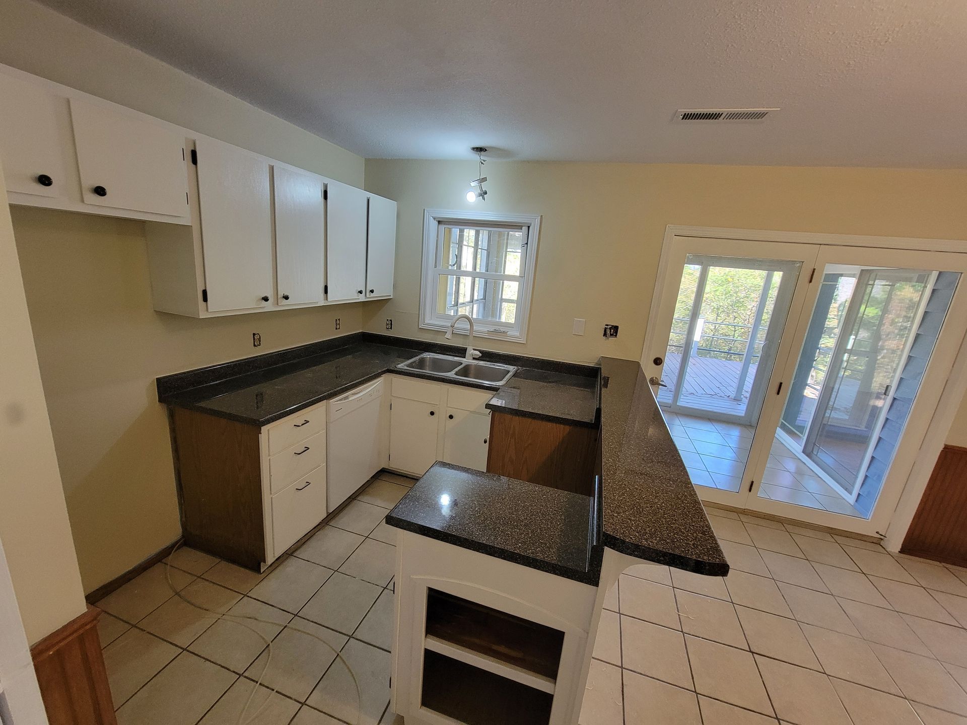 L-shaped kitchen with white cabinets, dark countertops, a breakfast bar, and sliding glass doors.