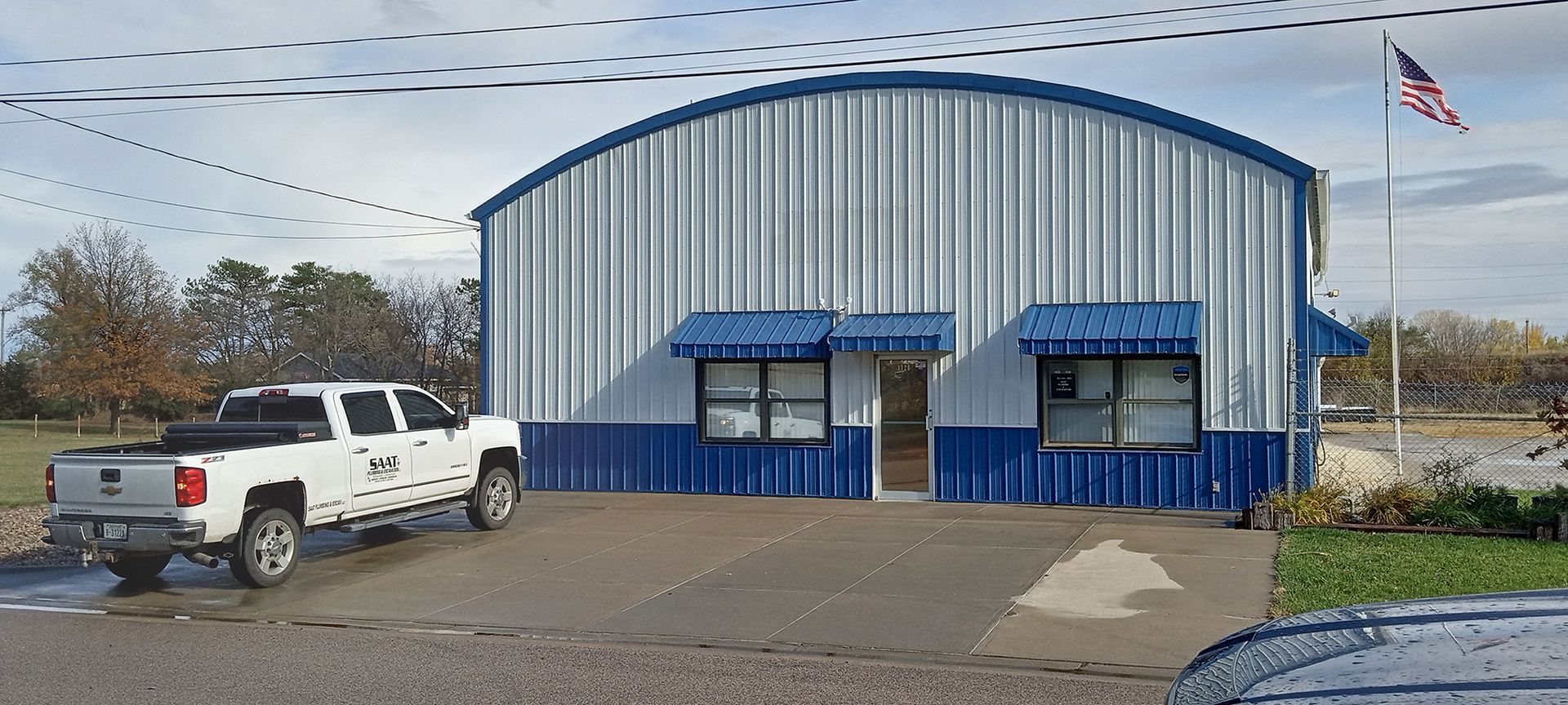 White truck parked in front of a blue and white building with an American flag.