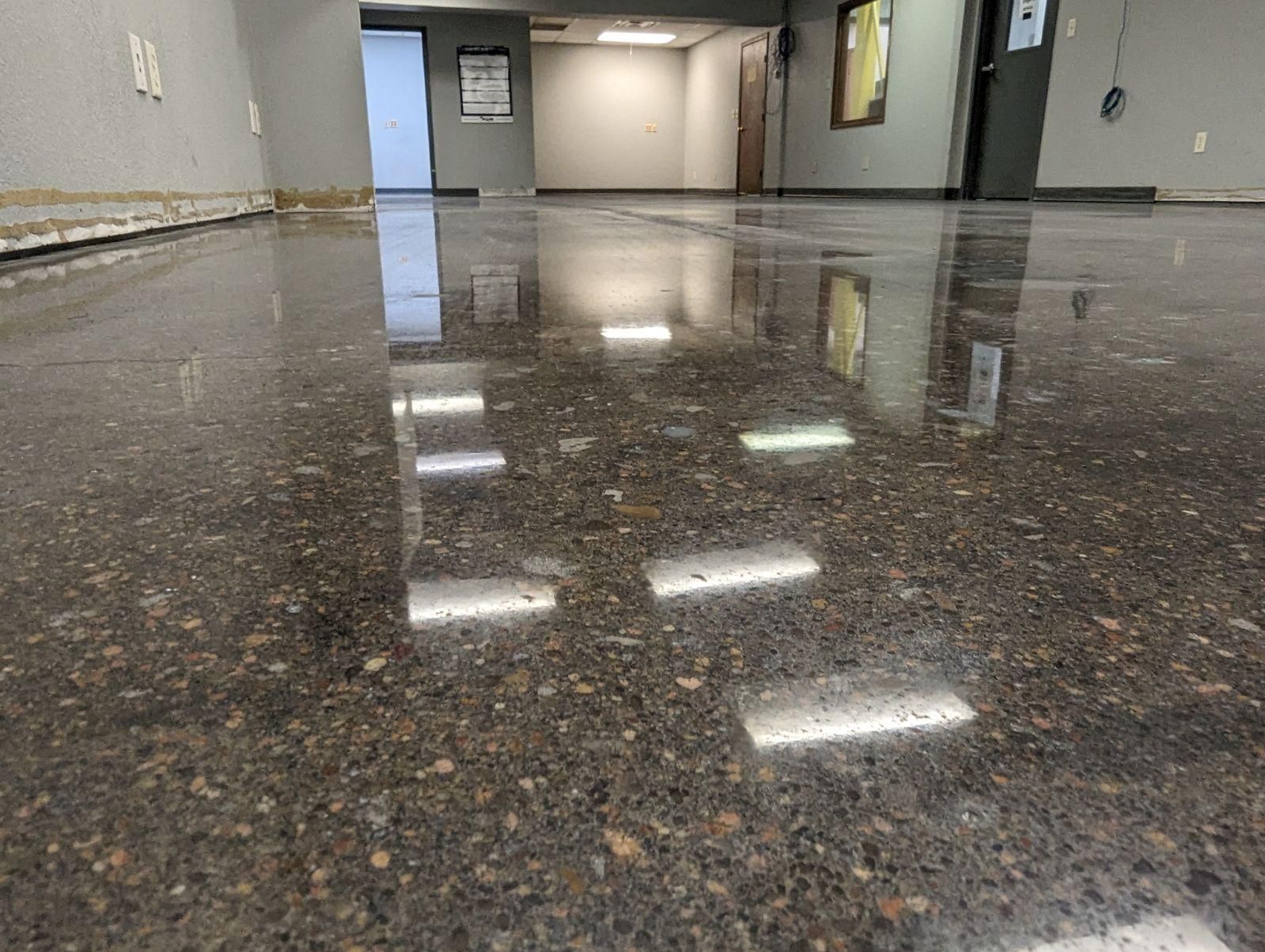 Polished concrete floor reflecting ceiling lights in an empty room.