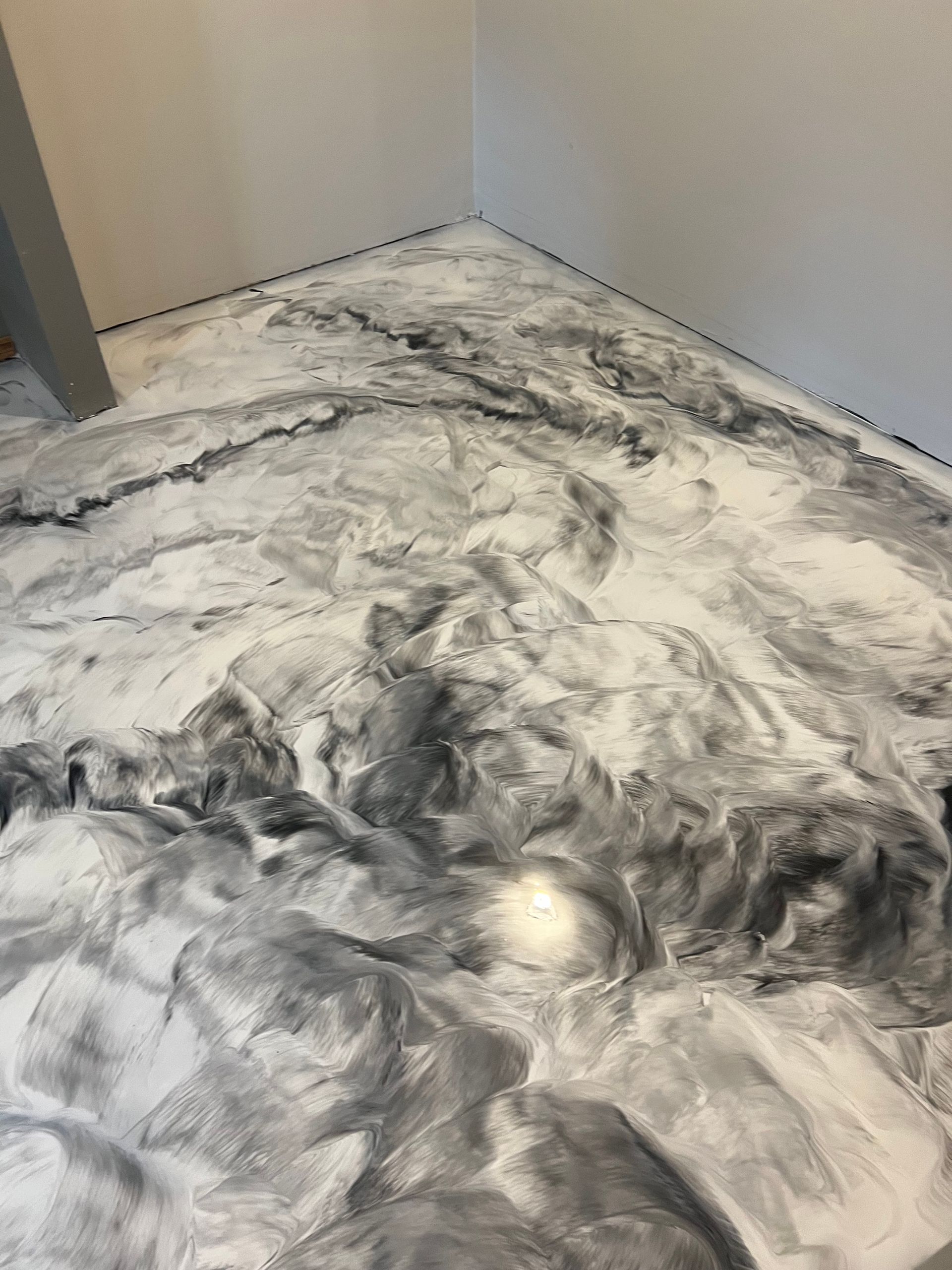 Grey and white marbled epoxy floor in a corner of a room.
