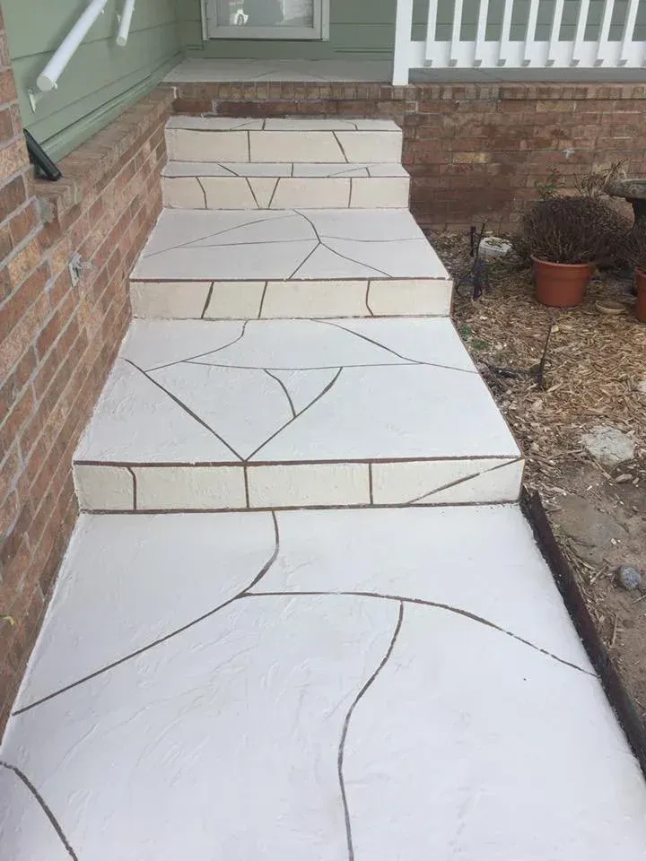 White tiled front steps leading up to a house. Brick wall on the left, foliage and pots on the right.