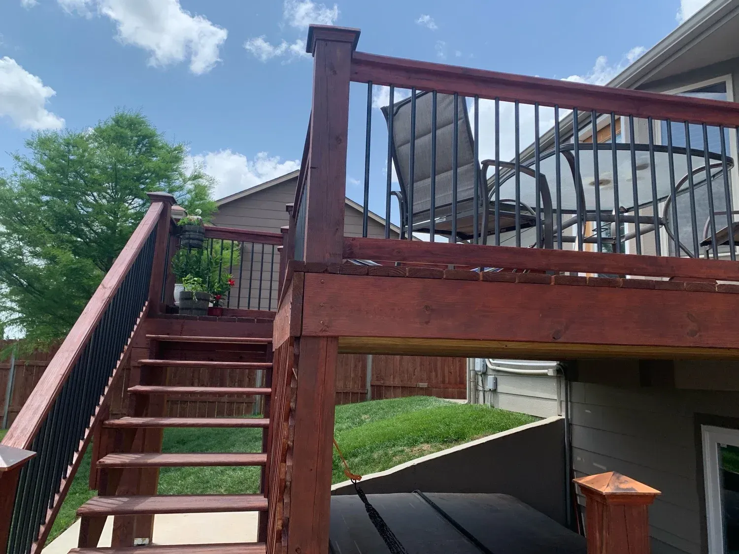 Wooden deck with stairs, railing, and outdoor furniture on a sunny day.