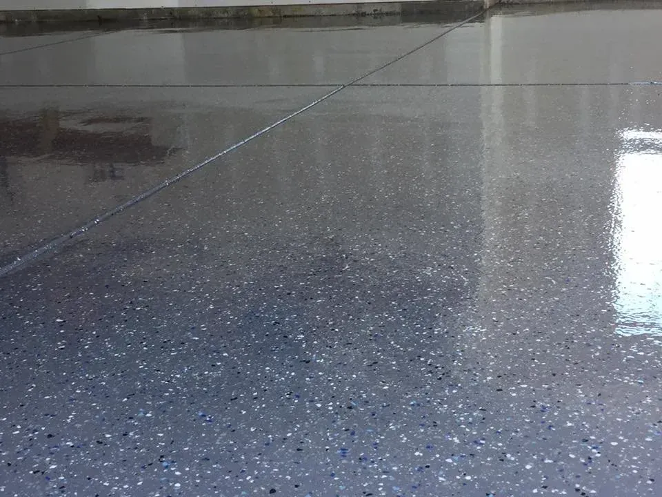 Epoxy garage floor with gray and flecked colors, reflecting light.