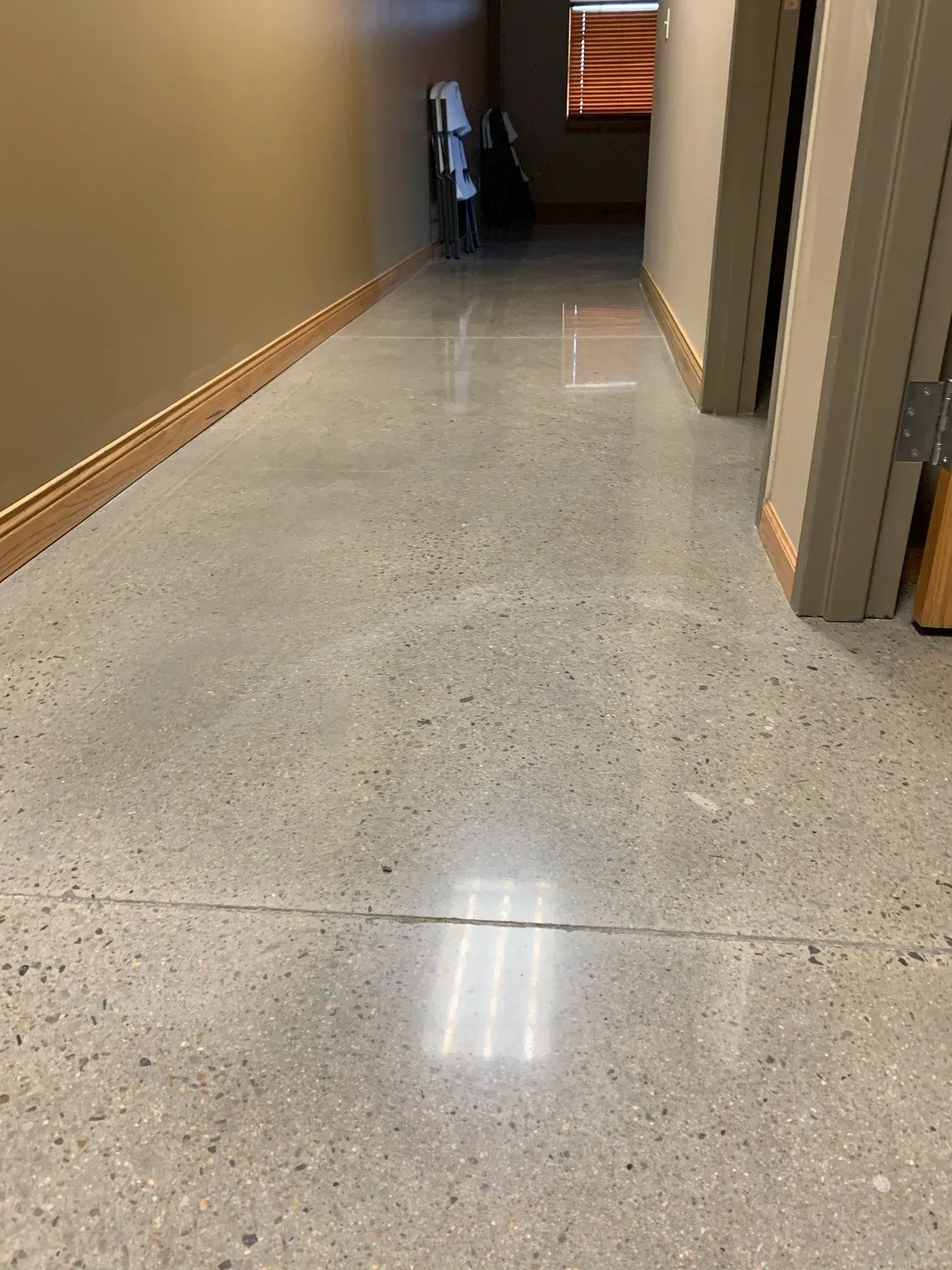 Hallway with polished concrete floor, tan walls, and a door on the right side.