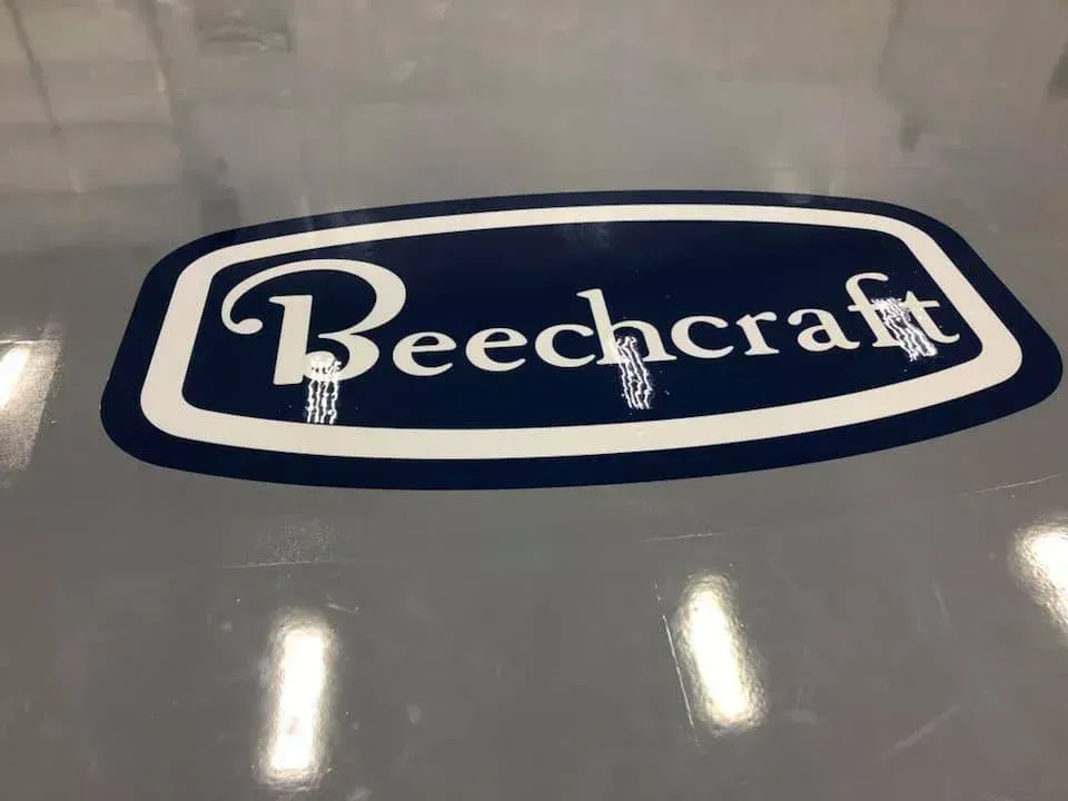Beechcraft logo in white text on a blue oval with a white border, on a gray surface.