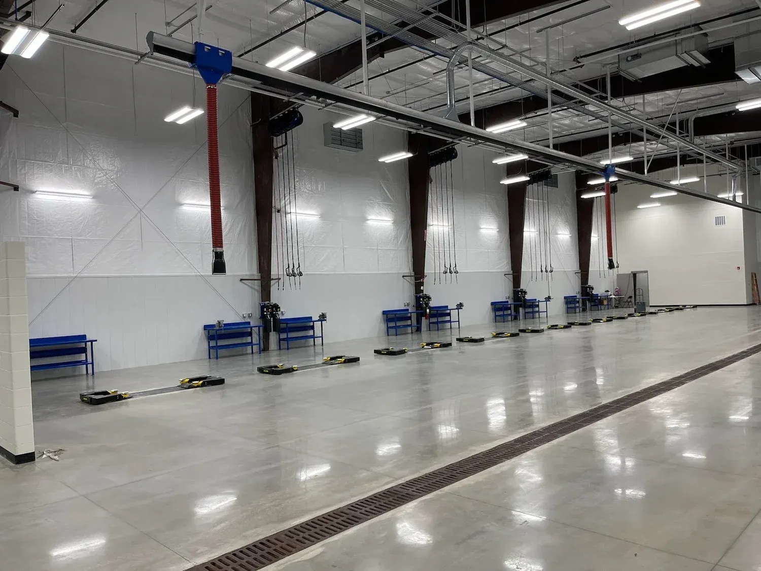 A service bay with equipment hanging from the ceiling. Benches and tools line the floor.