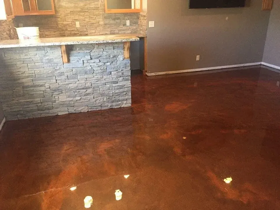 Metallic copper-colored epoxy floor in a room with a stacked stone bar and neutral walls.