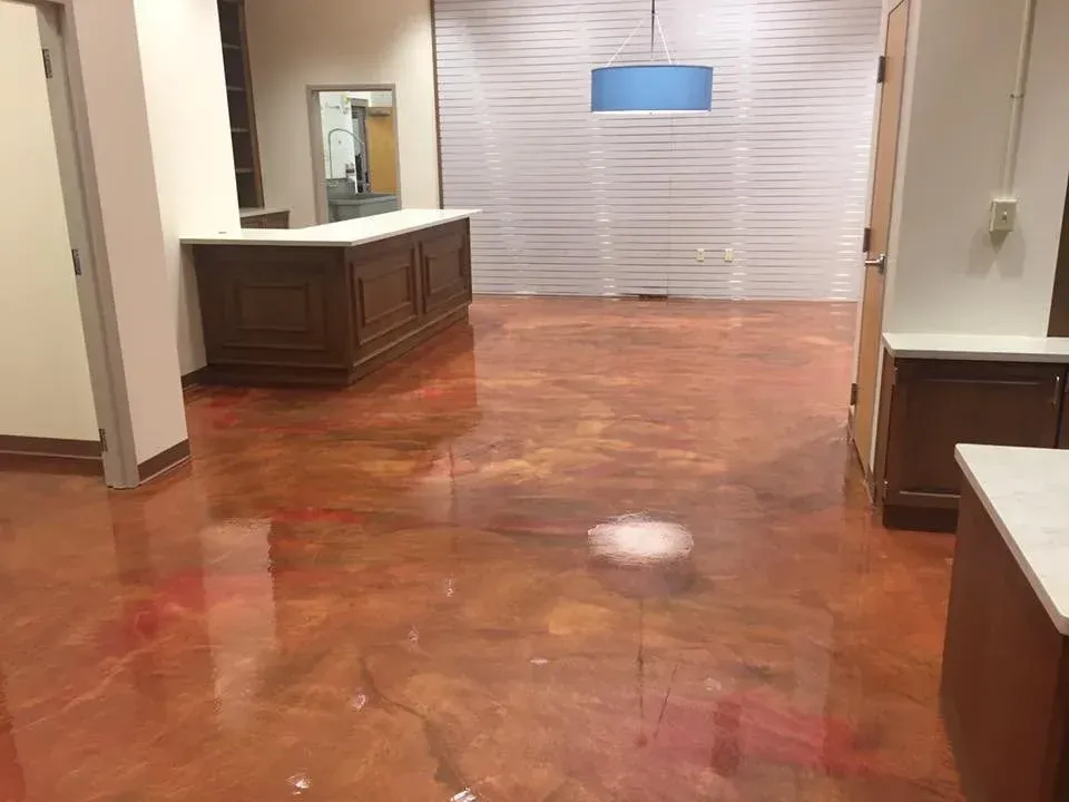 Shiny, metallic-look flooring in a room with a wooden counter and a white wall behind it.
