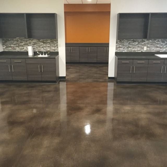 A room with dark cabinets, a shiny brown floor, and a colorful accent wall.