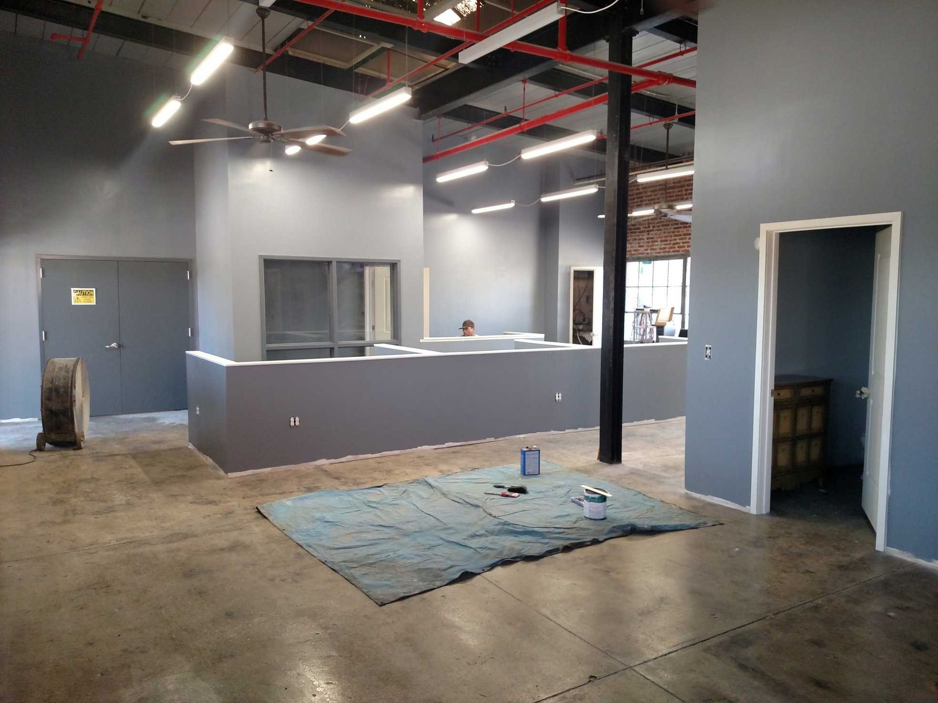 Interior view of a newly painted industrial space in gray tones, with a concrete floor and exposed ceiling.