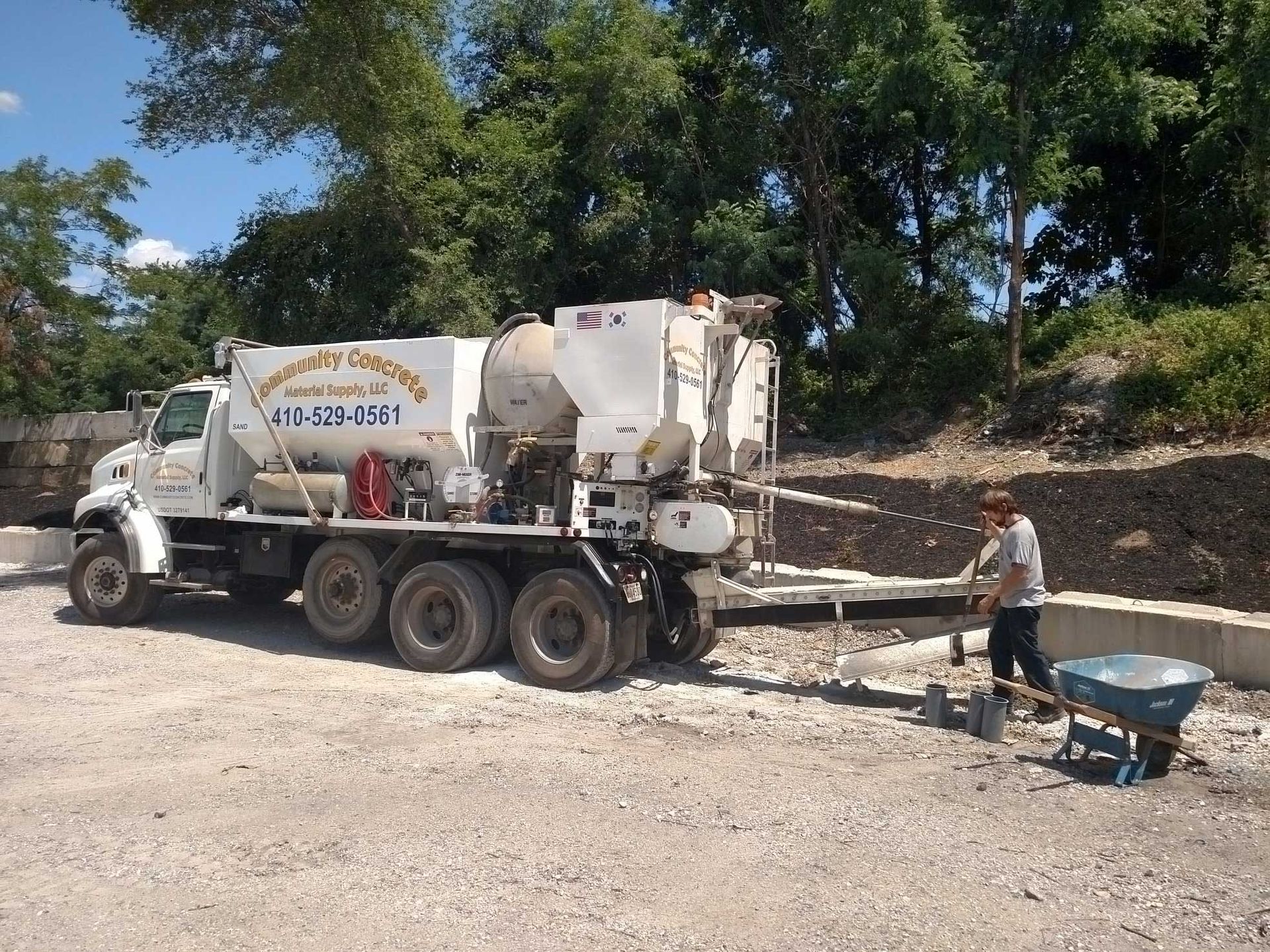 Concrete truck delivering concrete at a construction site; a worker shovels the material into a form.