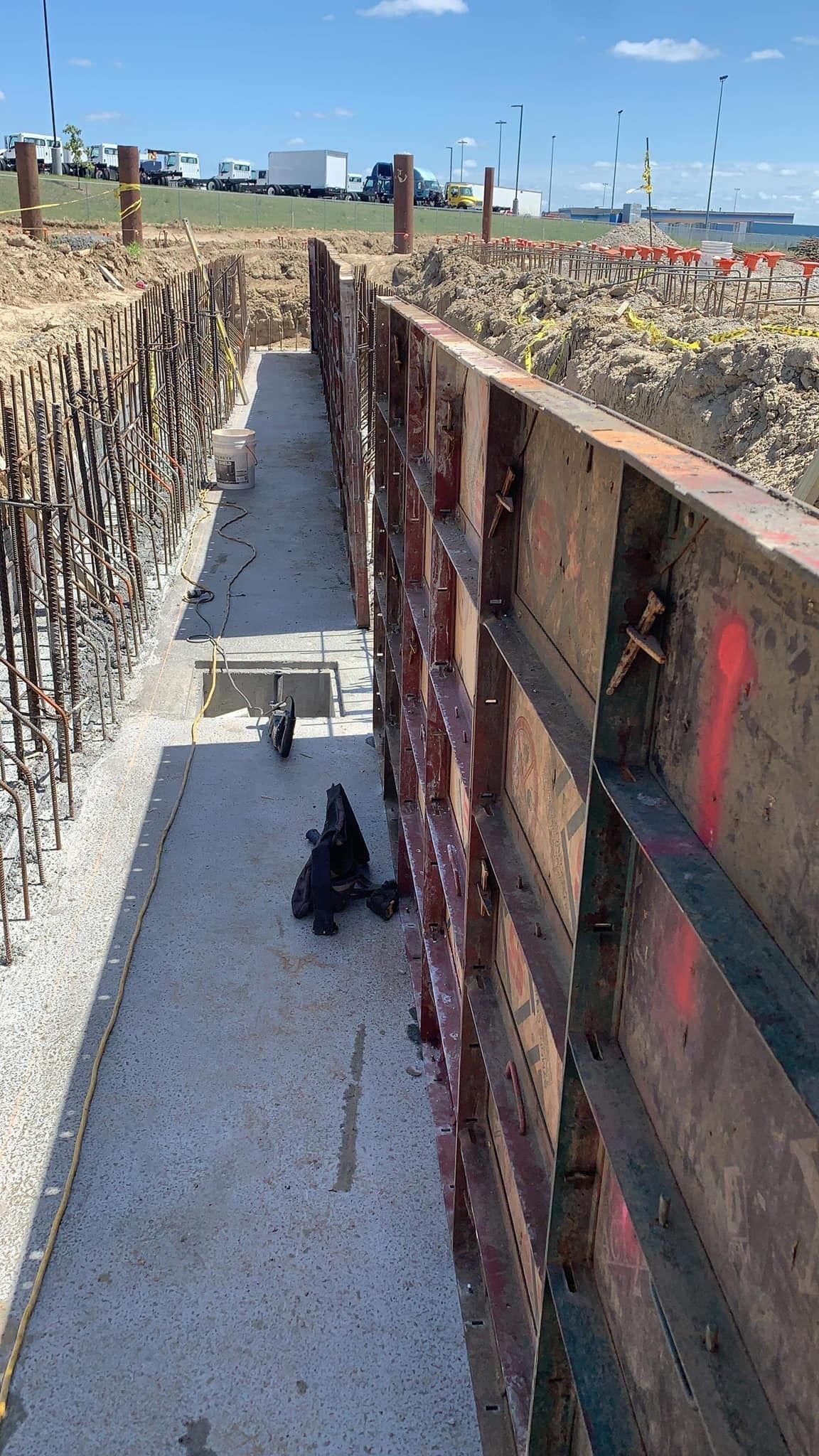 Construction site with a concrete trench, metal formwork, and exposed rebar.