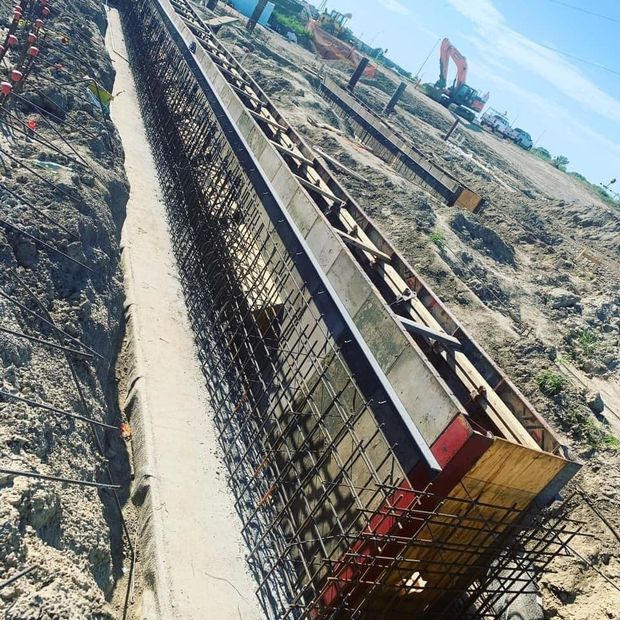 Construction site trench with rebar framework and wooden formwork prepared for concrete.