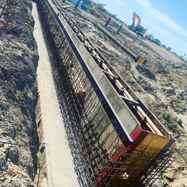 Construction site trench with rebar framework and wooden formwork prepared for concrete.